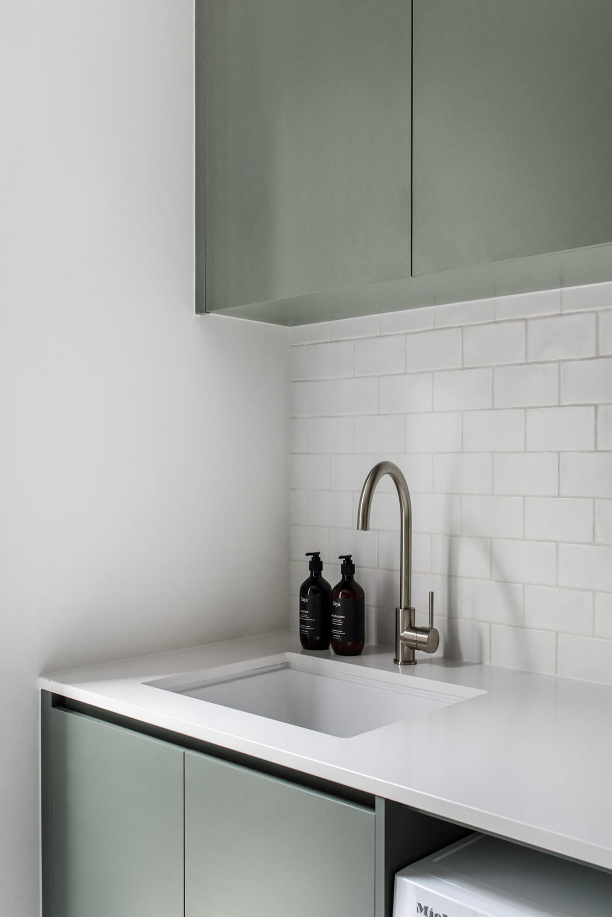 A custom designed laundry featuring green joinery. Designed and built by MJ Harris Group.
