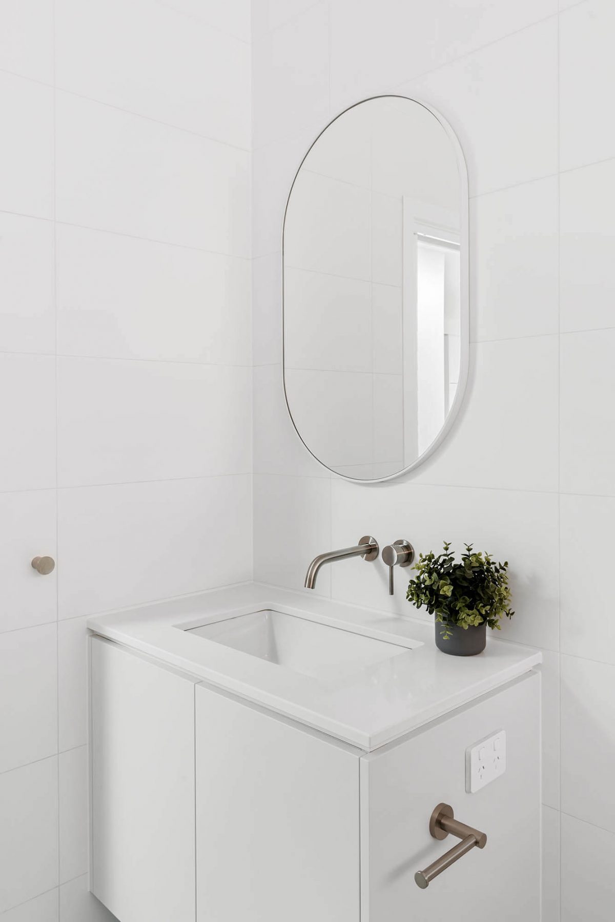 A custom designed ensuite bathroom featuring a white vanity and oval mirror. Designed and built by MJ Harris Group. #MJHxEdinburghSt