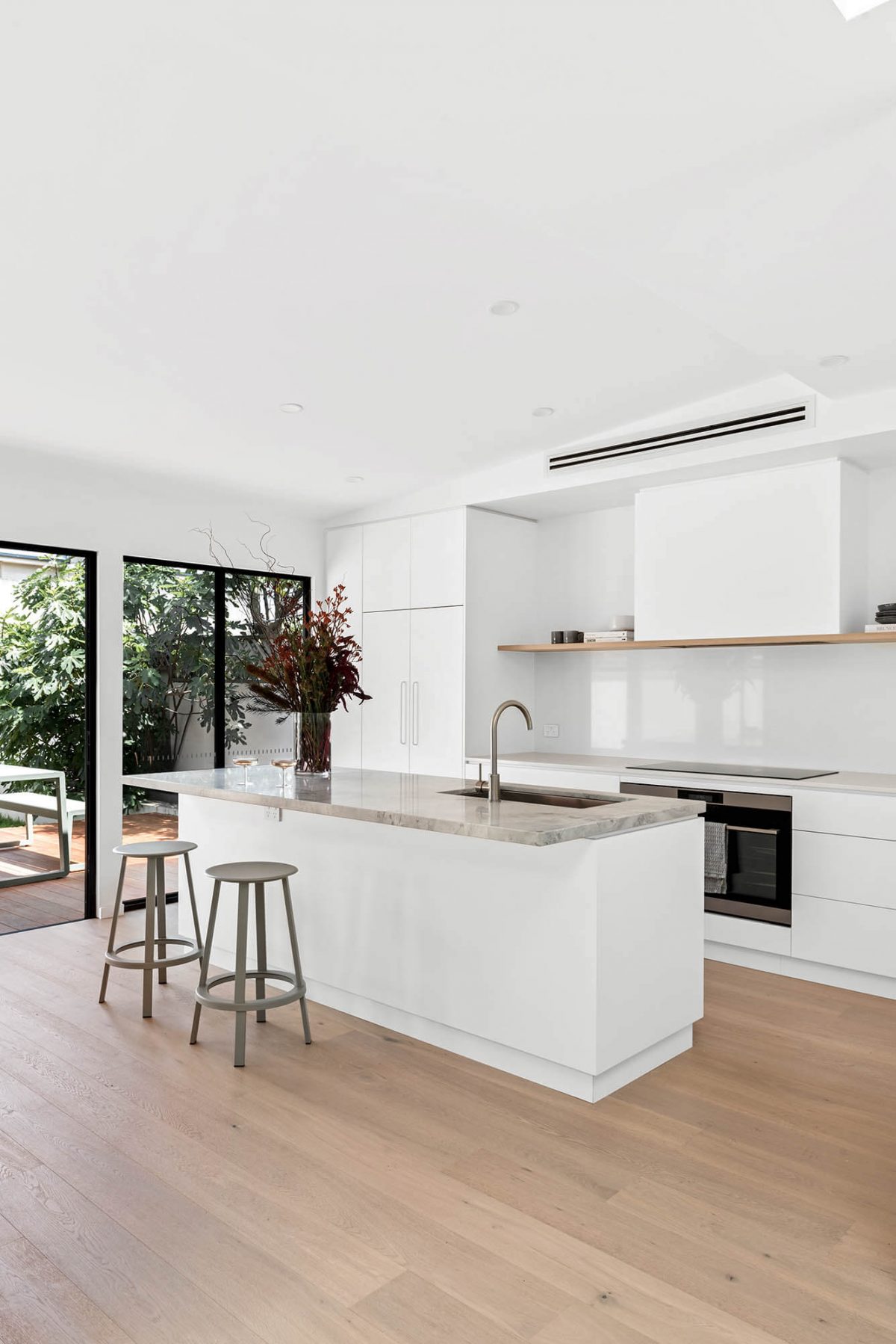 A custom designed kitchen featuring a stone benchtop and white custom joinery. Designed and built by MJ Harris Group. #MJHxEdinburghSt