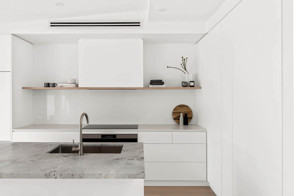 A custom designed kitchen featuring a stone benchtop and white custom joinery. Designed and built by MJ Harris Group. #MJHxEdinburghSt