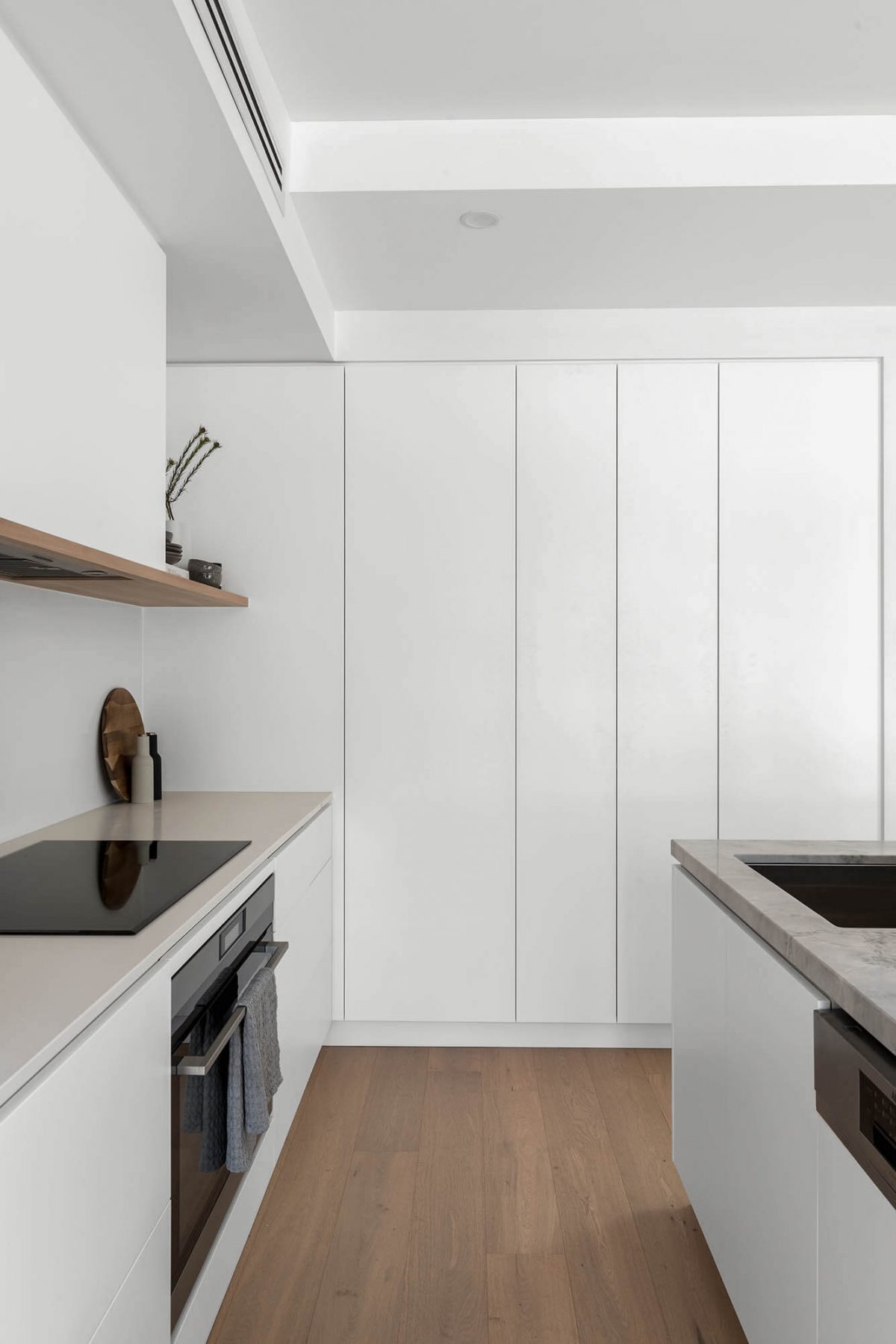 A custom designed kitchen featuring a stone benchtop and white custom joinery. Designed and built by MJ Harris Group. #MJHxEdinburghSt