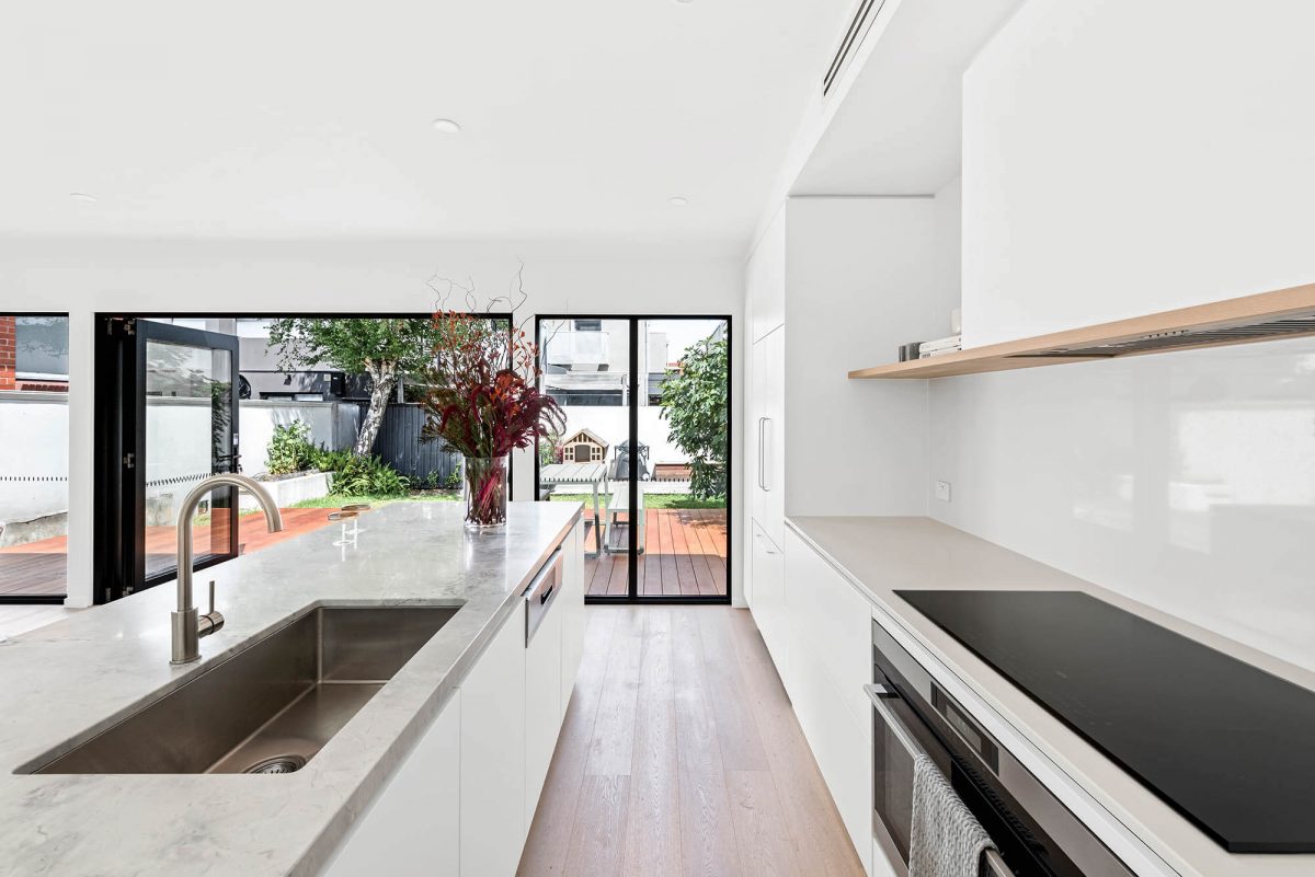 A custom designed kitchen featuring a stone benchtop and white custom joinery. Designed and built by MJ Harris Group. #MJHxEdinburghSt