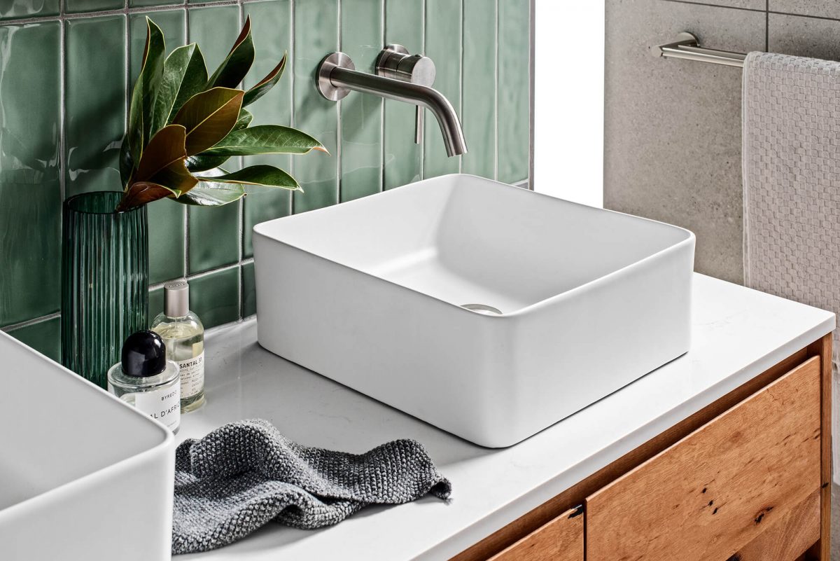 A custom designed laundry featuring green tiles. Designed and built by MJ Harris Group.