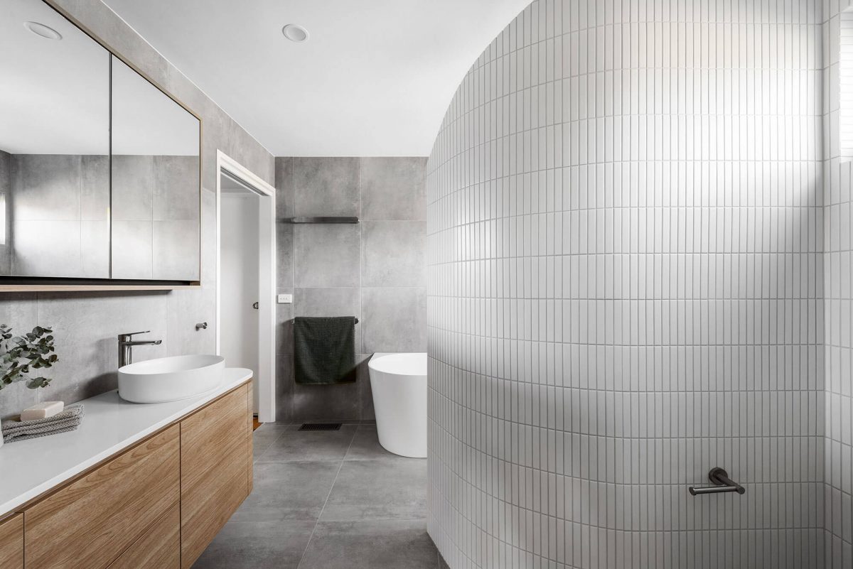 A custom designed Jack and Jill bathroom with a curved wall shower. Designed and built by MJ Harris Group.