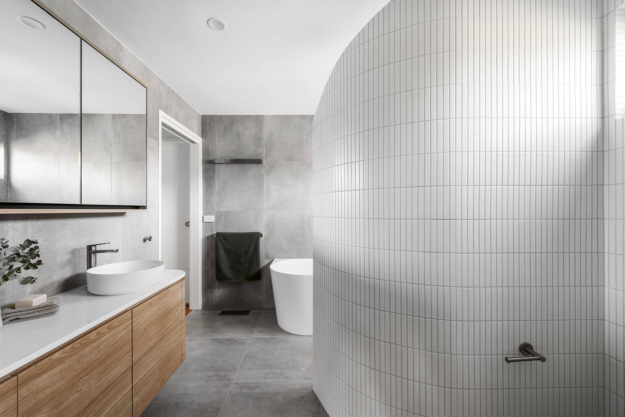 A custom designed Jack and Jill bathroom with a curved wall shower. Designed and built by MJ Harris Group.