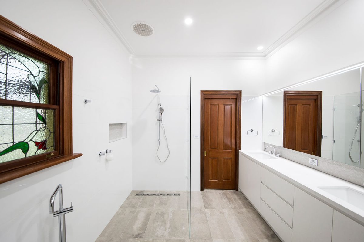 A custom designed bathroom featuring a timber door and a walk in shower. Designed and built by MJ Harris Group.