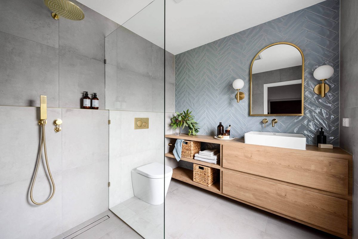 A custom designed bathroom featuring blue tiles in a herringbone pattern. Designed and built by MJ Harris Group.