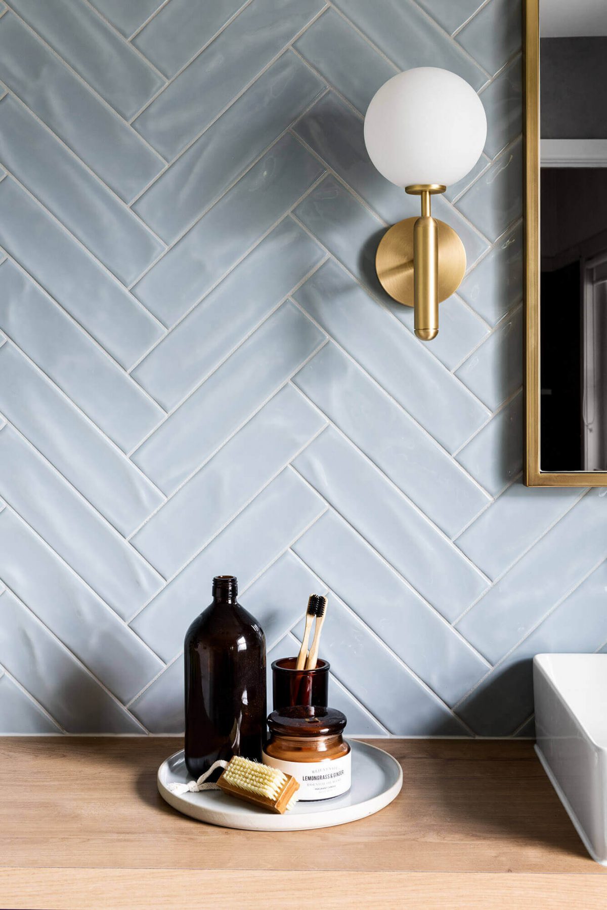 A custom designed bathroom featuring blue tiles in a herringbone pattern. Designed and built by MJ Harris Group.