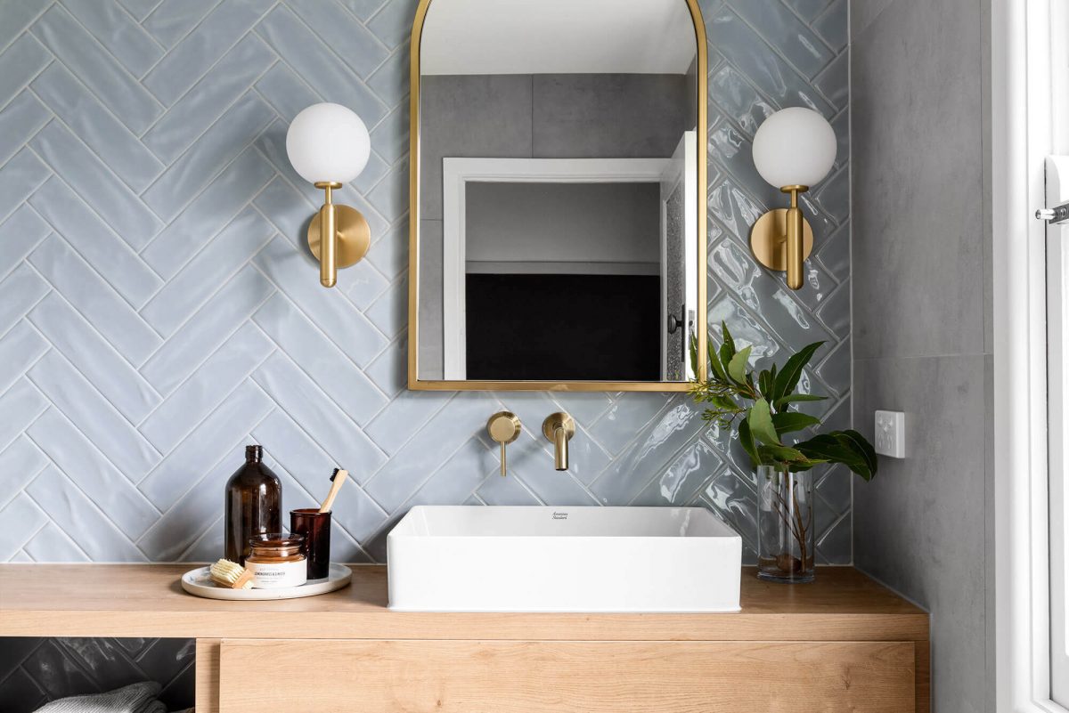 A custom designed bathroom featuring blue tiles in a herringbone pattern. Designed and built by MJ Harris Group.