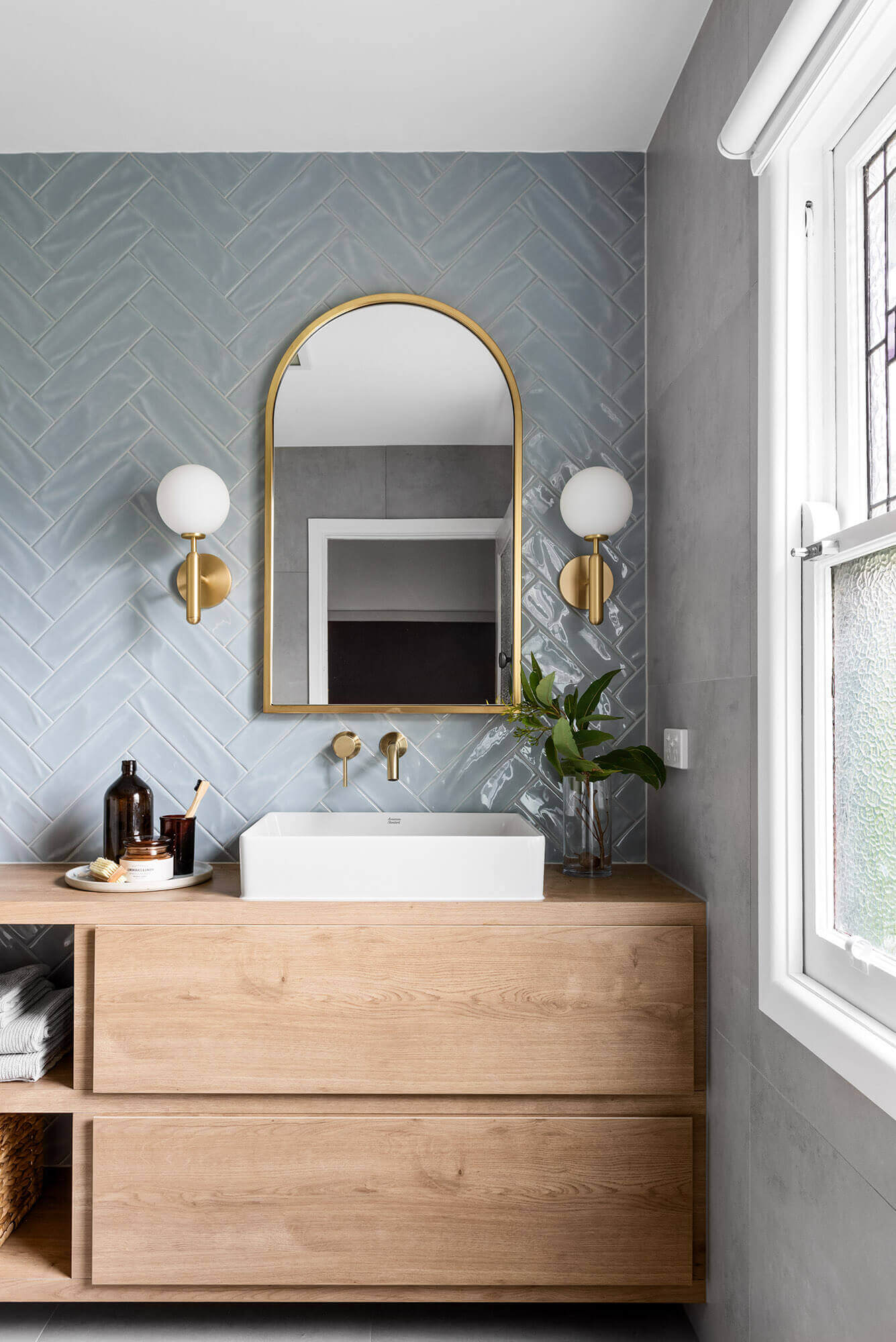 A custom designed bathroom featuring blue tiles in a herringbone pattern. Designed and built by MJ Harris Group.