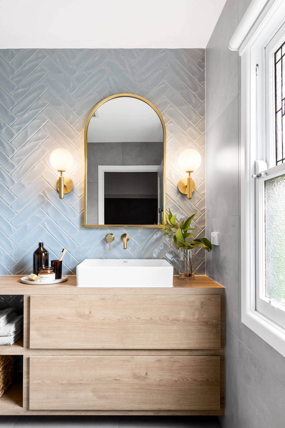 A custom designed bathroom featuring blue tiles in a herringbone pattern. Designed and built by MJ Harris Group.