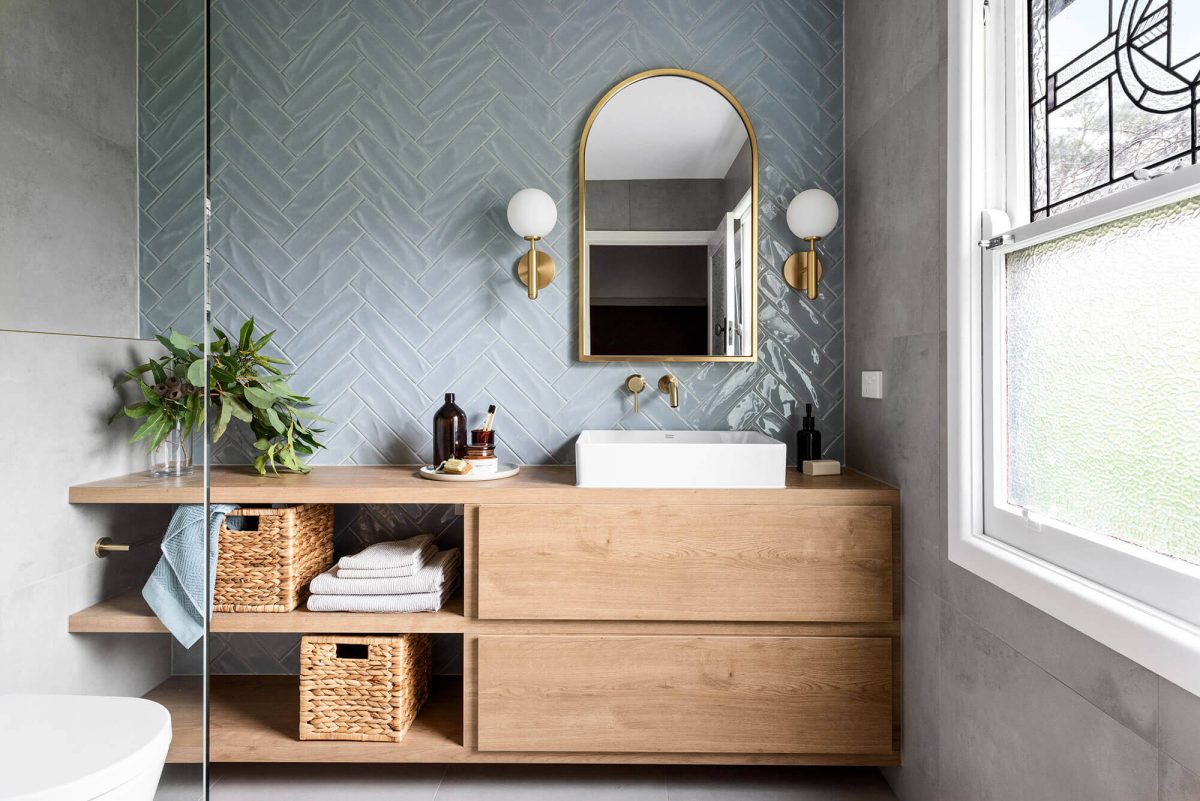 A custom designed bathroom featuring blue tiles in a herringbone pattern. Designed and built by MJ Harris Group.