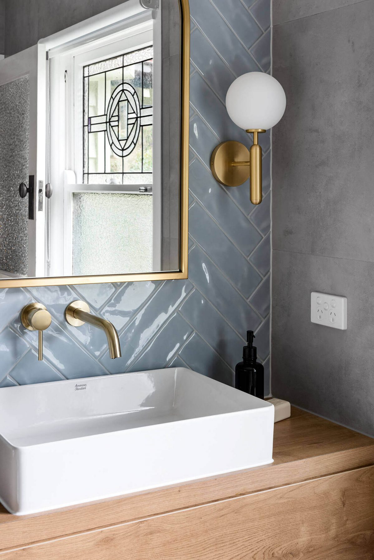 A custom designed bathroom featuring blue tiles in a herringbone pattern. Designed and built by MJ Harris Group.