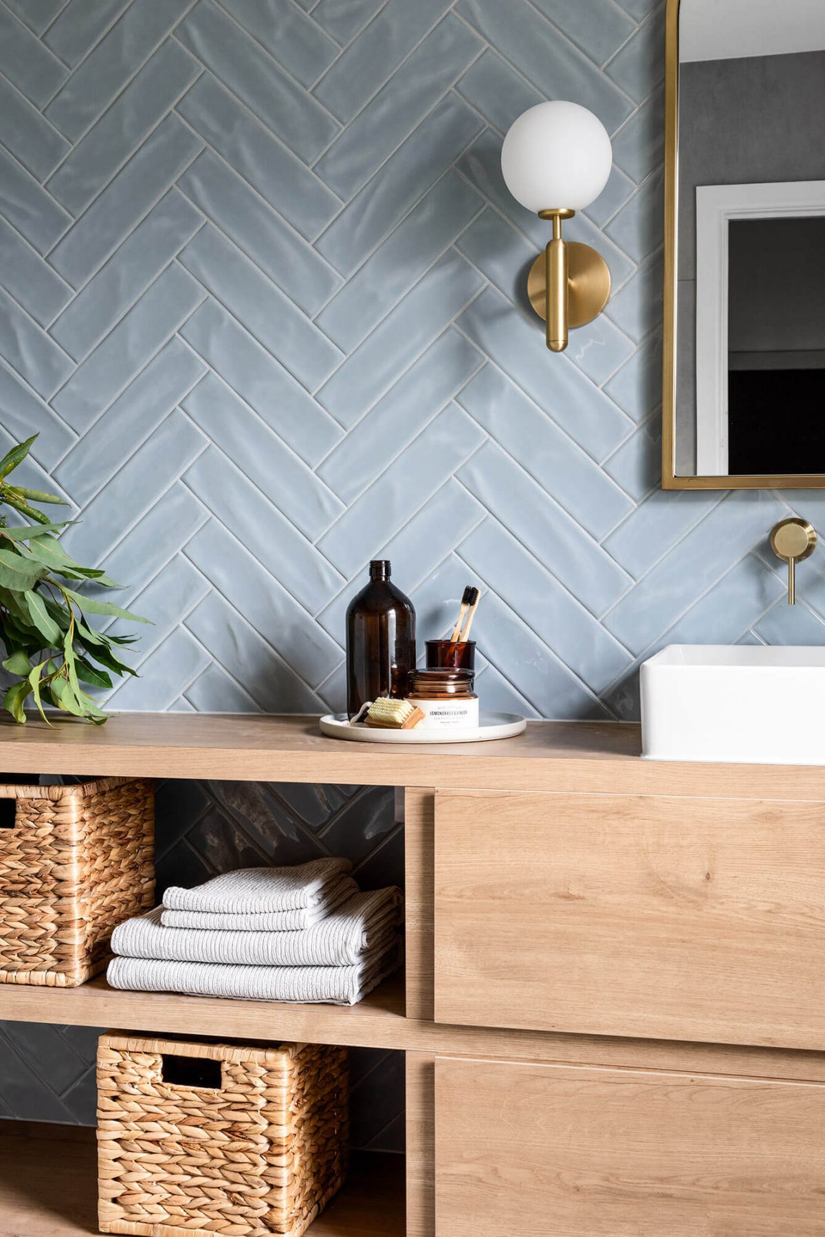 A custom designed bathroom featuring blue tiles in a herringbone pattern. Designed and built by MJ Harris Group.