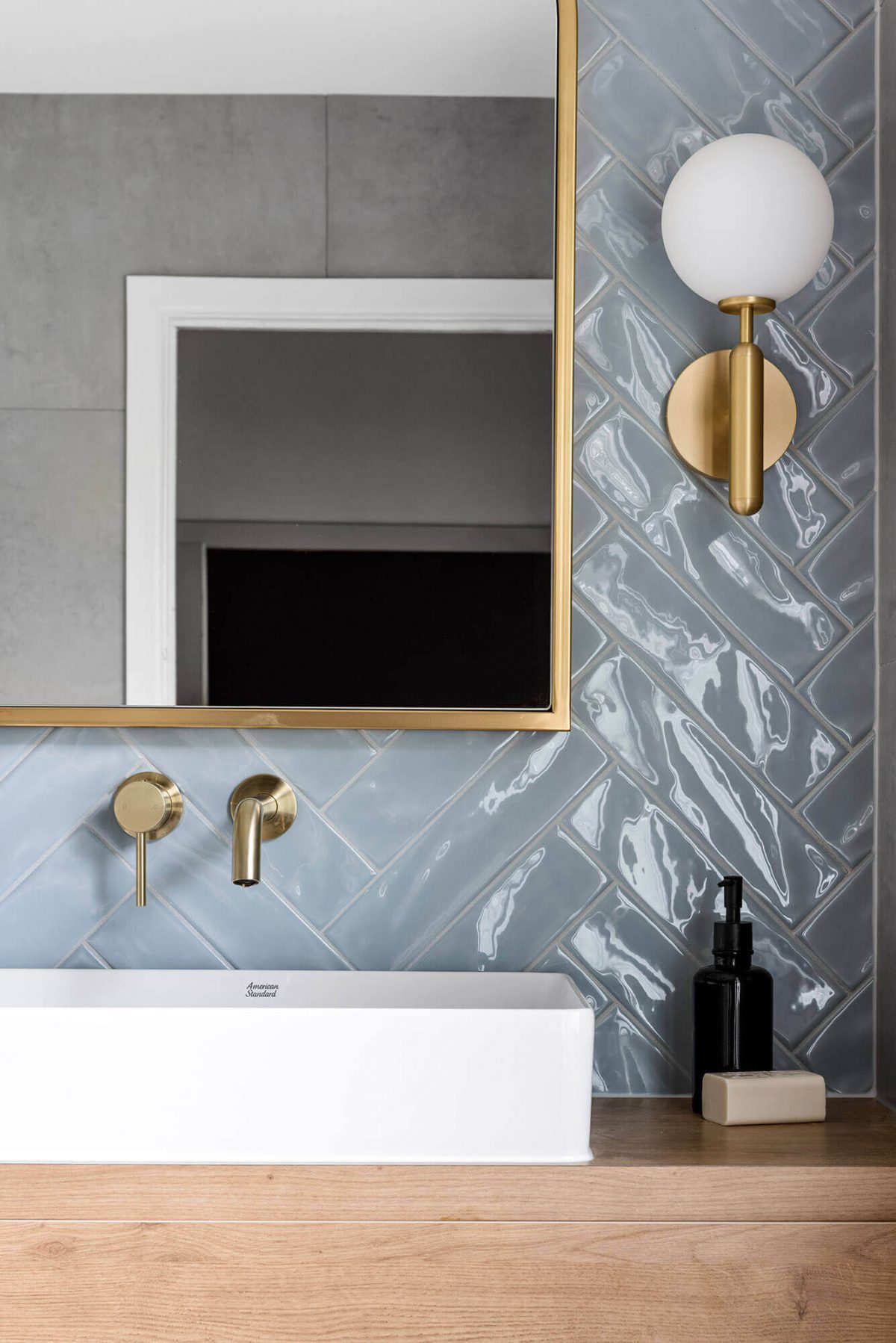 A custom designed bathroom featuring blue tiles in a herringbone pattern. Designed and built by MJ Harris Group.