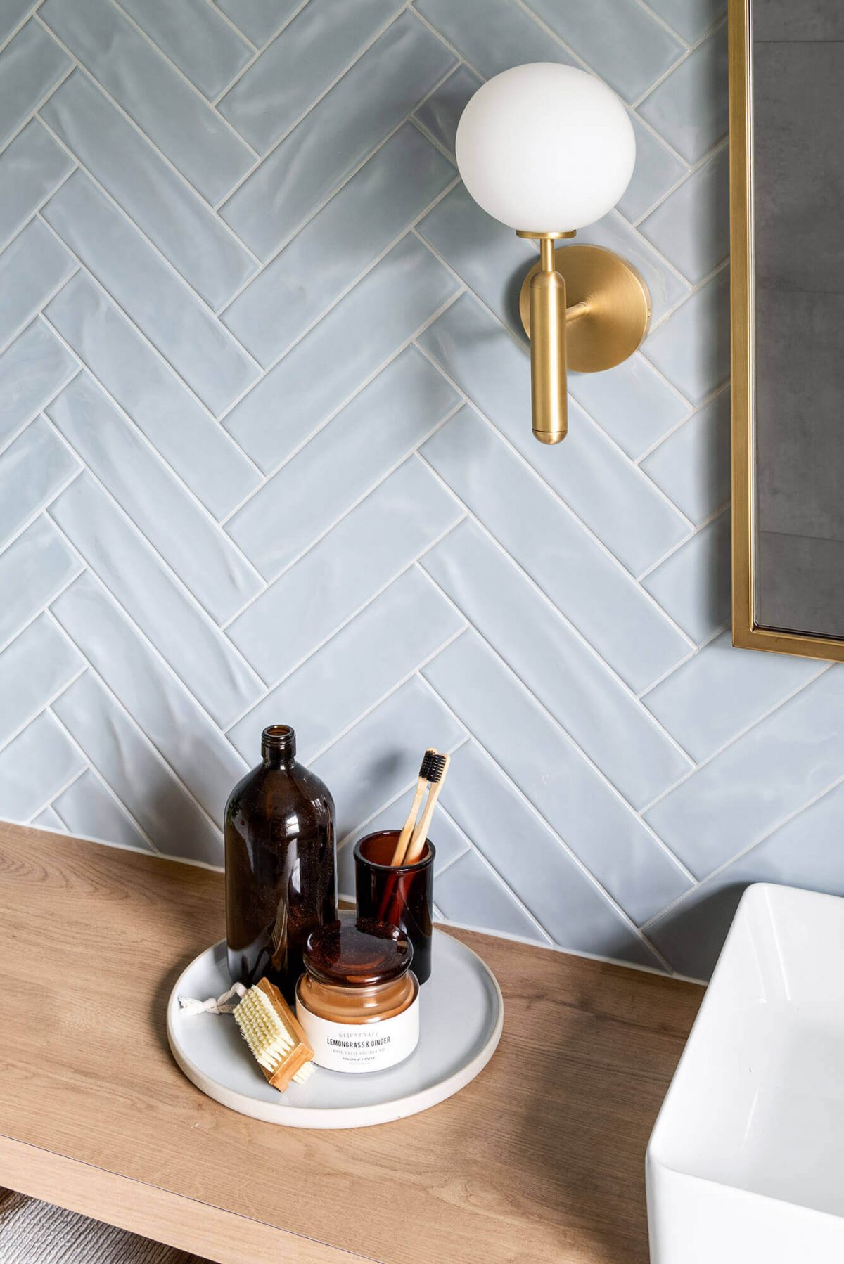A custom designed bathroom featuring blue tiles in a herringbone pattern. Designed and built by MJ Harris Group.