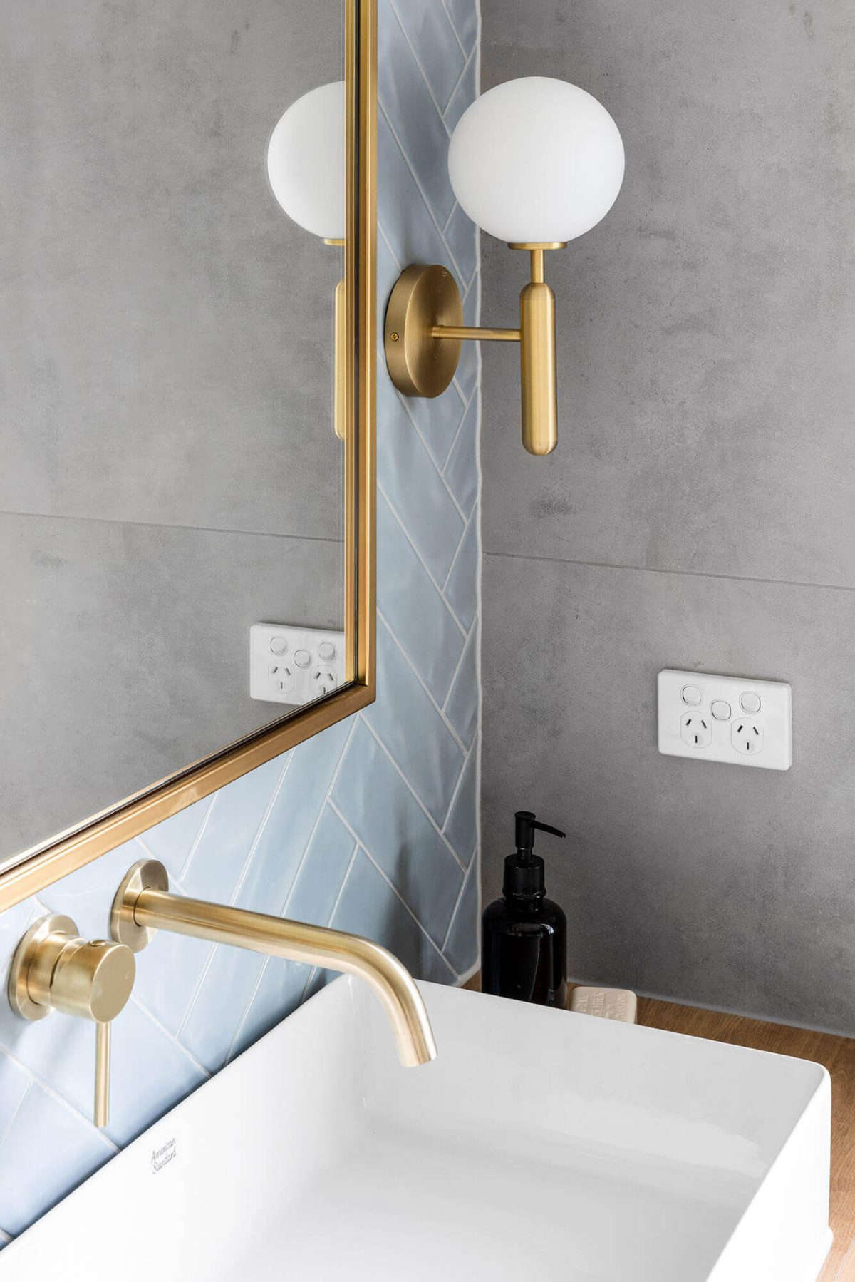 A custom designed bathroom featuring blue tiles in a herringbone pattern. Designed and built by MJ Harris Group.