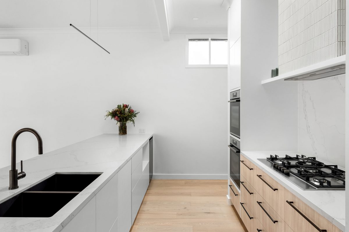 A custom designed kitchen featuring white Kit Kat files and brushed gunmetal tapware. Designed and built by MJ Harris Group. #MJHxBallantyneSt