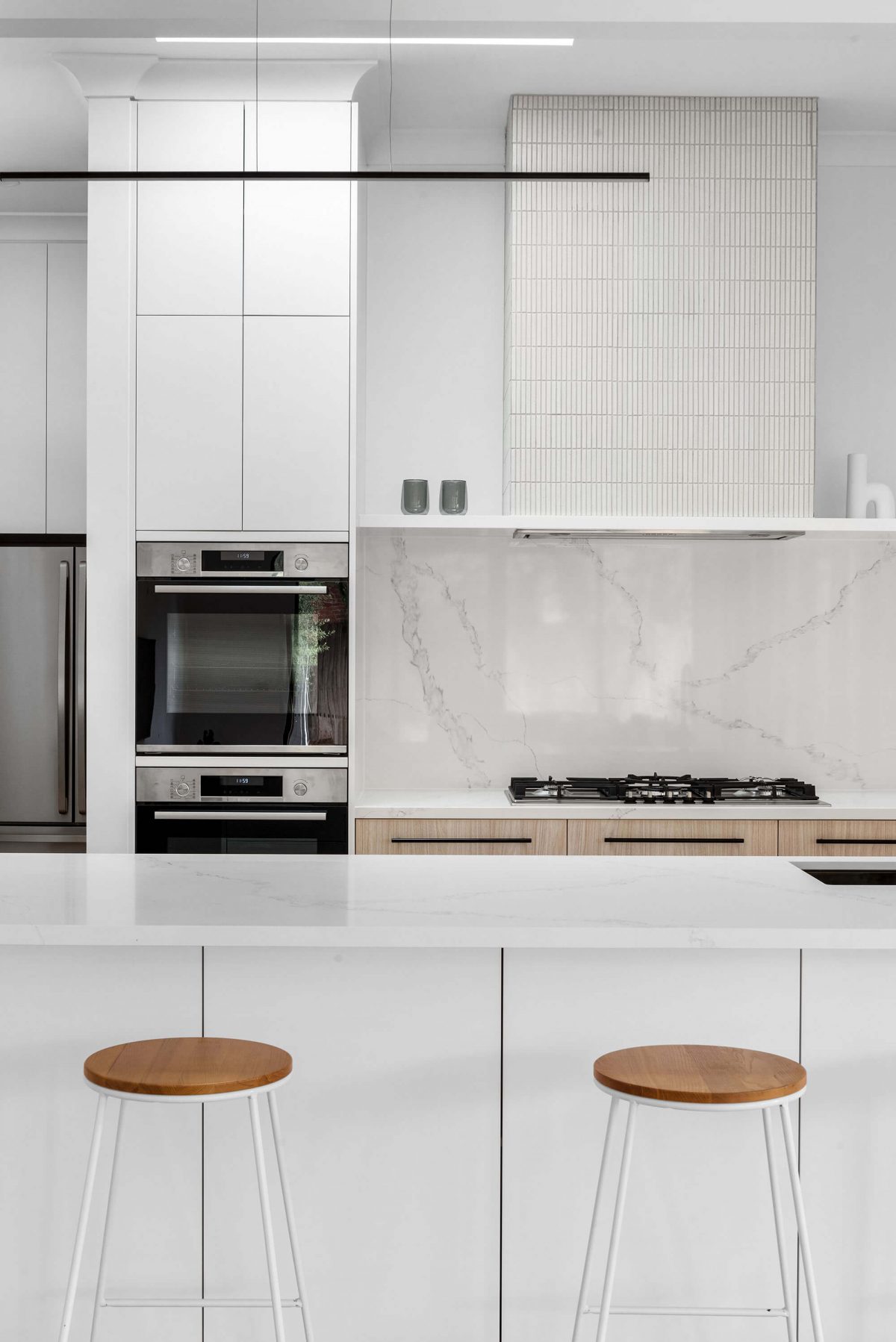A custom designed kitchen featuring white Kit Kat files and brushed gunmetal tapware. Designed and built by MJ Harris Group. #MJHxBallantyneSt