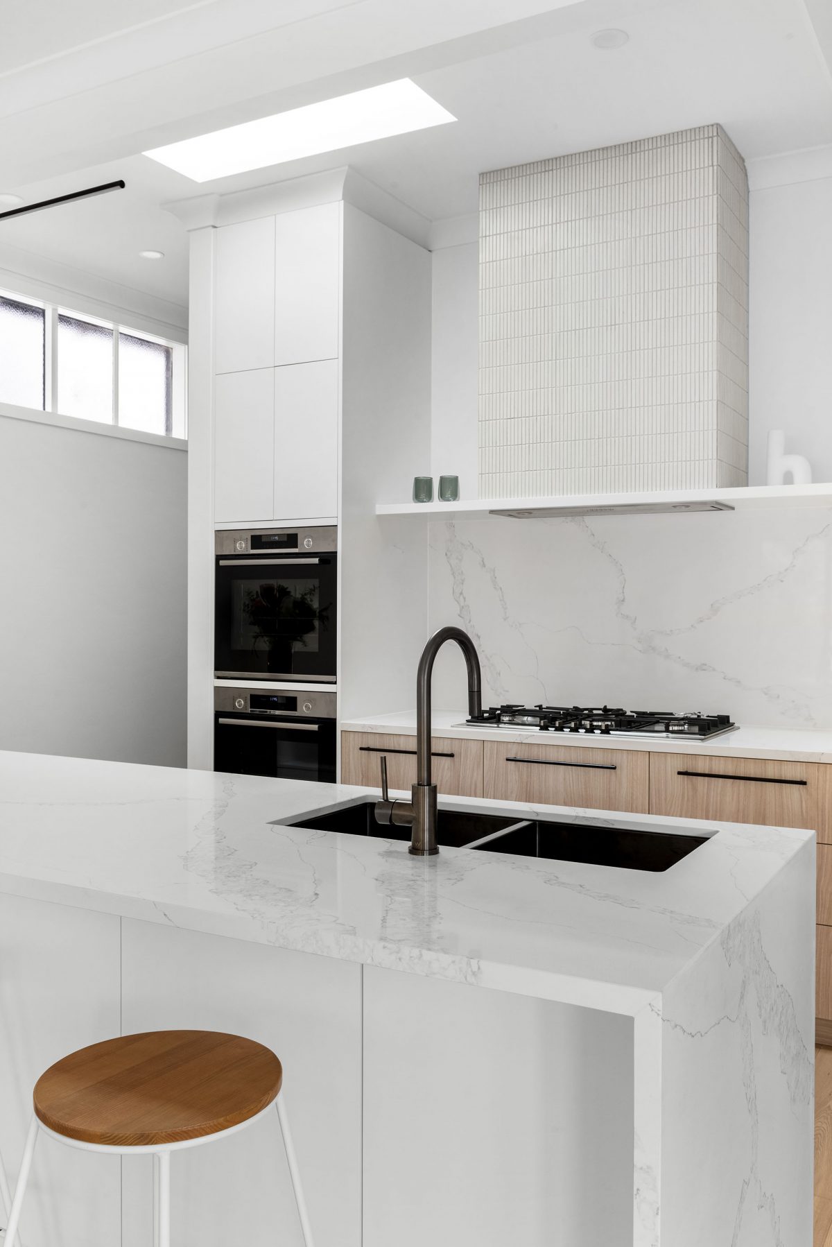 A custom designed kitchen featuring white Kit Kat files and brushed gunmetal tapware. Designed and built by MJ Harris Group. #MJHxBallantyneSt