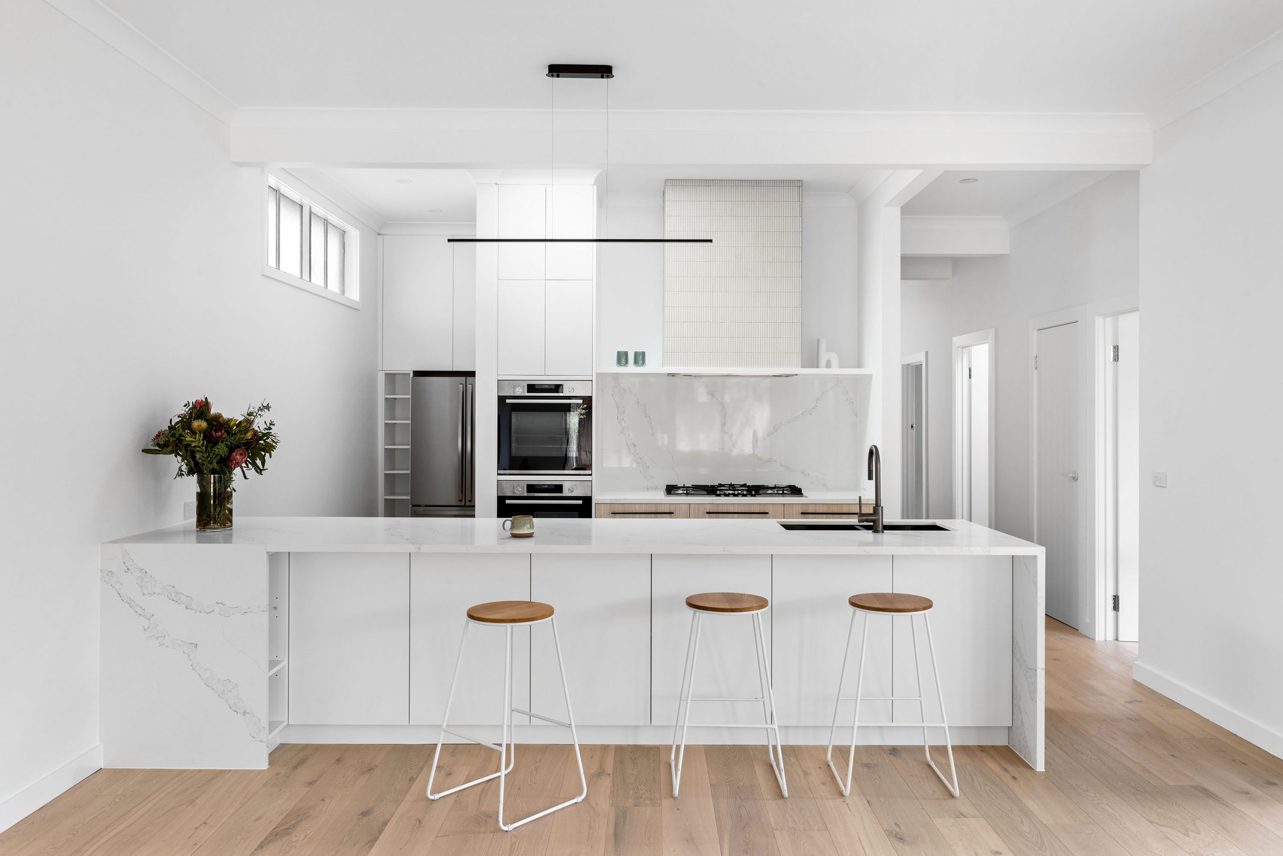 A custom designed kitchen featuring white Kit Kat files and brushed gunmetal tapware. Designed and built by MJ Harris Group. #MJHxBallantyneSt