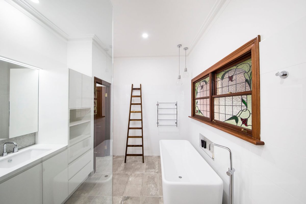 A custom designed bathroom featuring a timber doorframe and a free standing bath. Designed and built by MJ Harris Group.