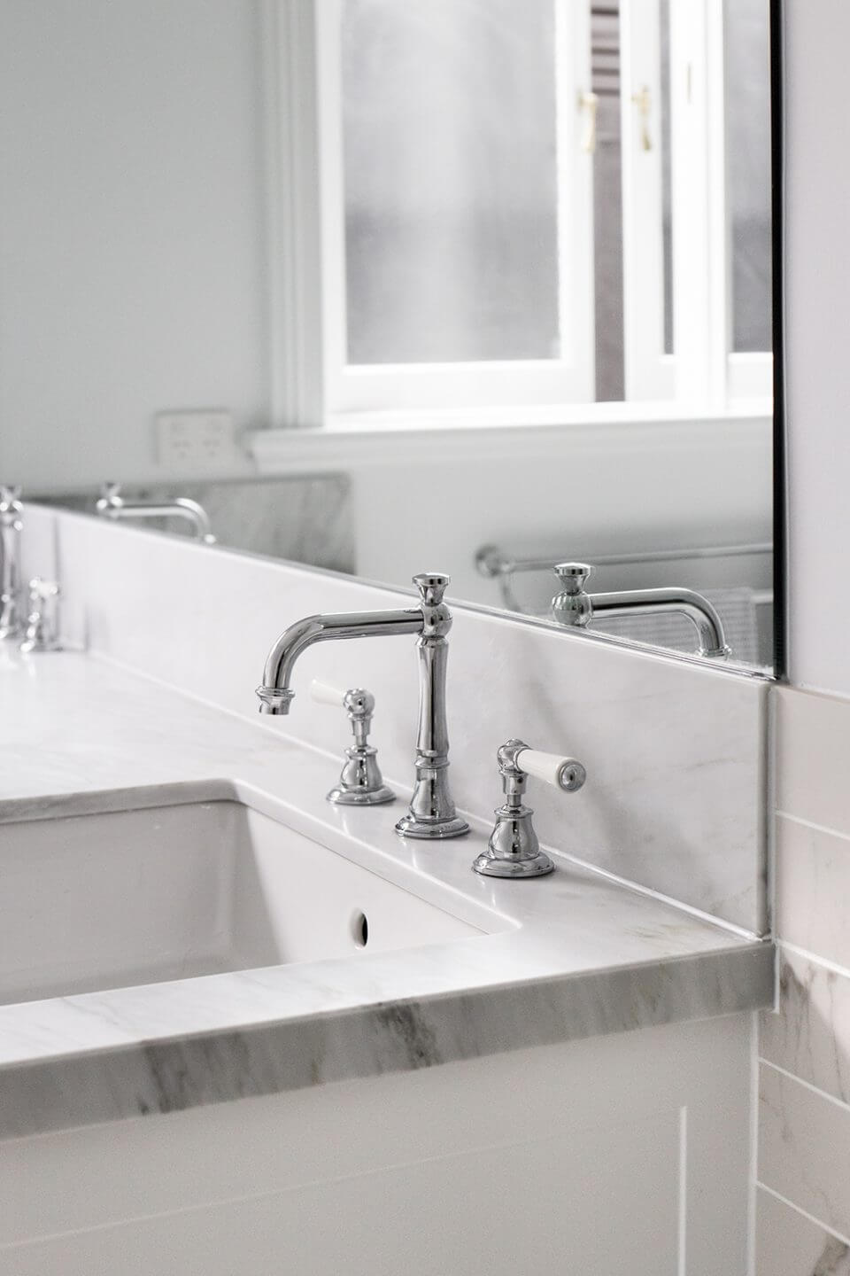A custom designed bathroom featuring chrome fixtures. Designed and built by MJ Harris Group.