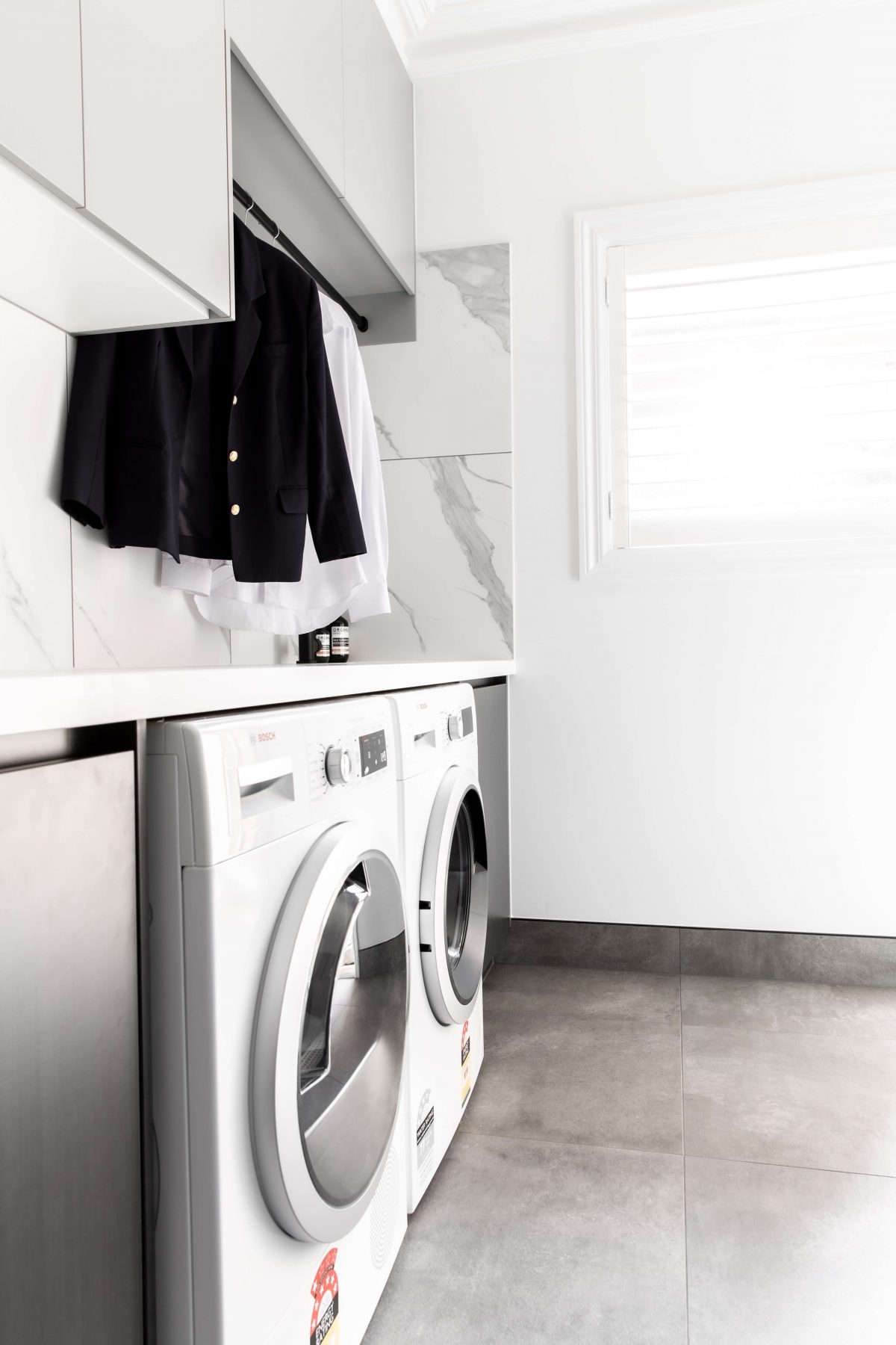 A custom designed laundry featuring marble look tiles. Designed and built by MJ Harris Group.