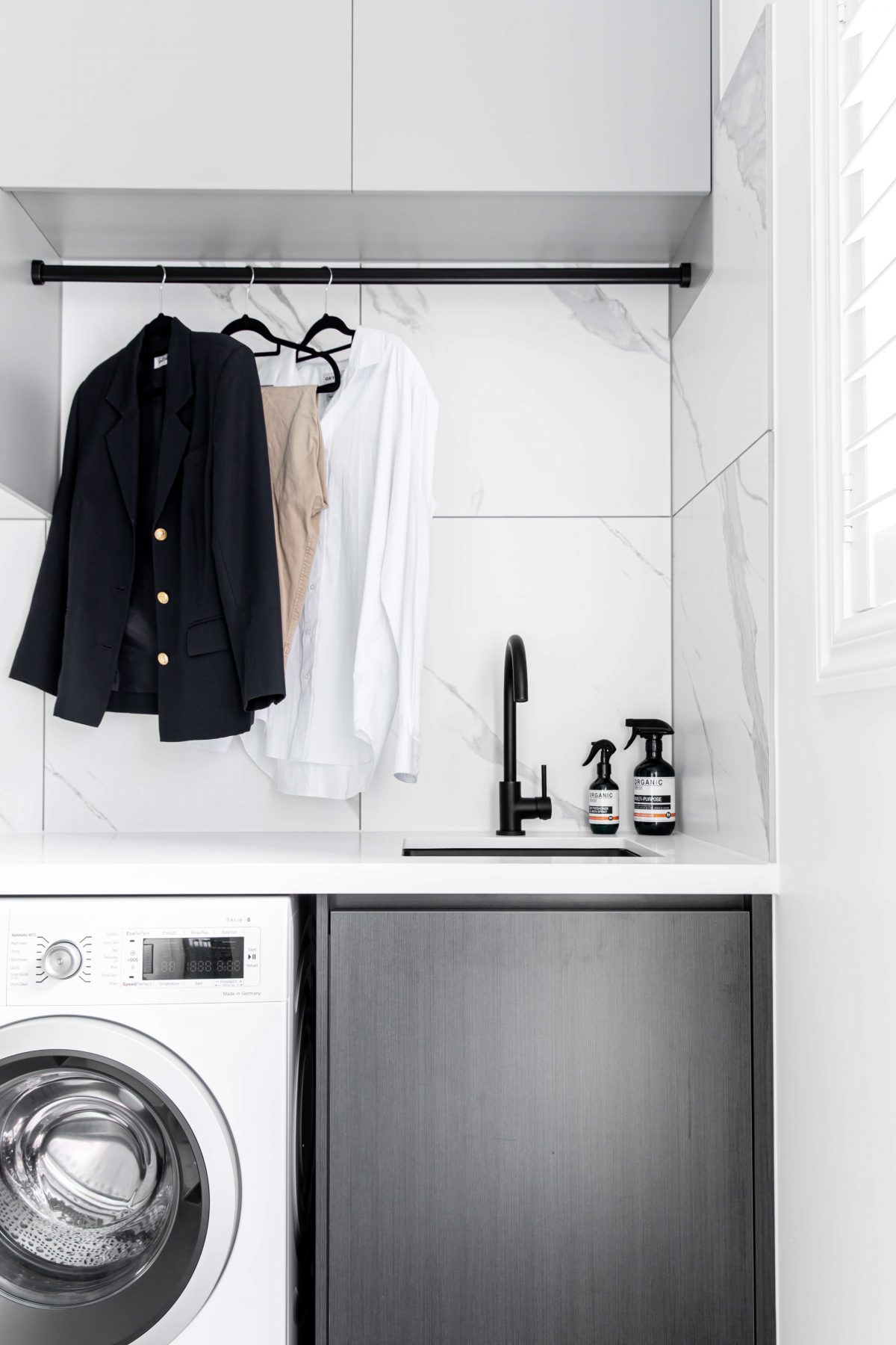 A custom designed laundry featuring marble look tiles. Designed and built by MJ Harris Group.