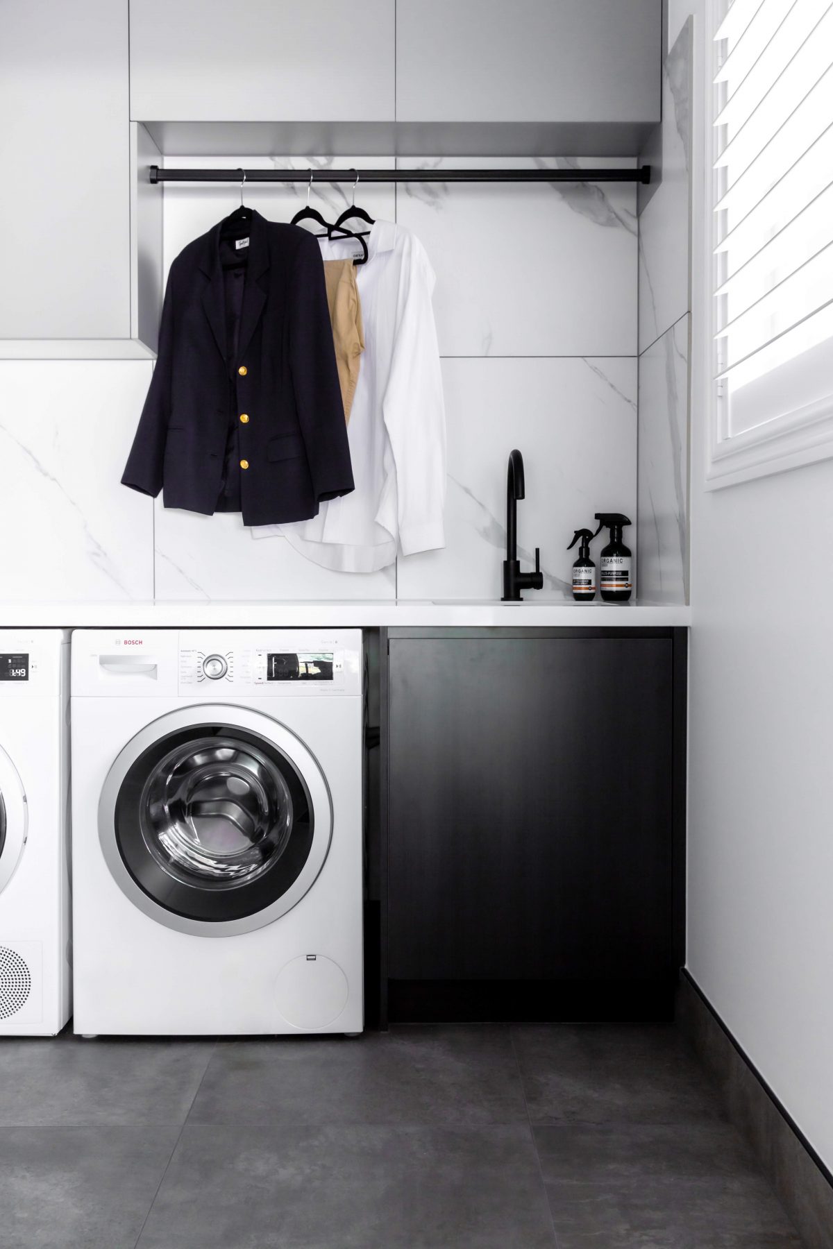 A custom designed laundry featuring marble look tiles. Designed and built by MJ Harris Group.