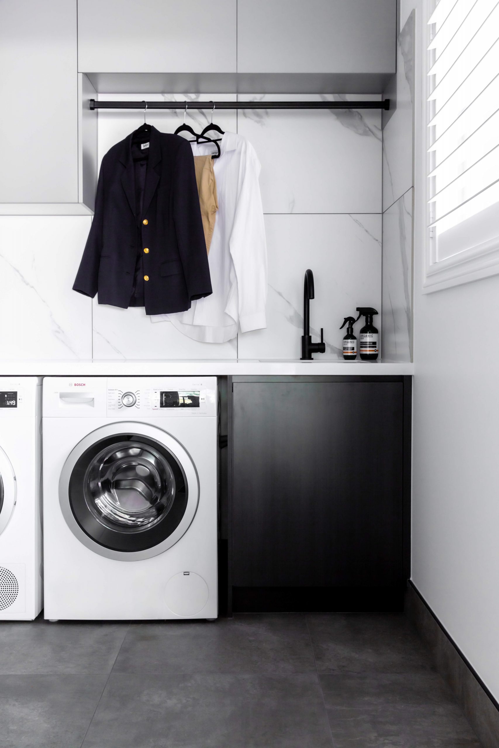 A custom designed laundry featuring marble look tiles. Designed and built by MJ Harris Group.