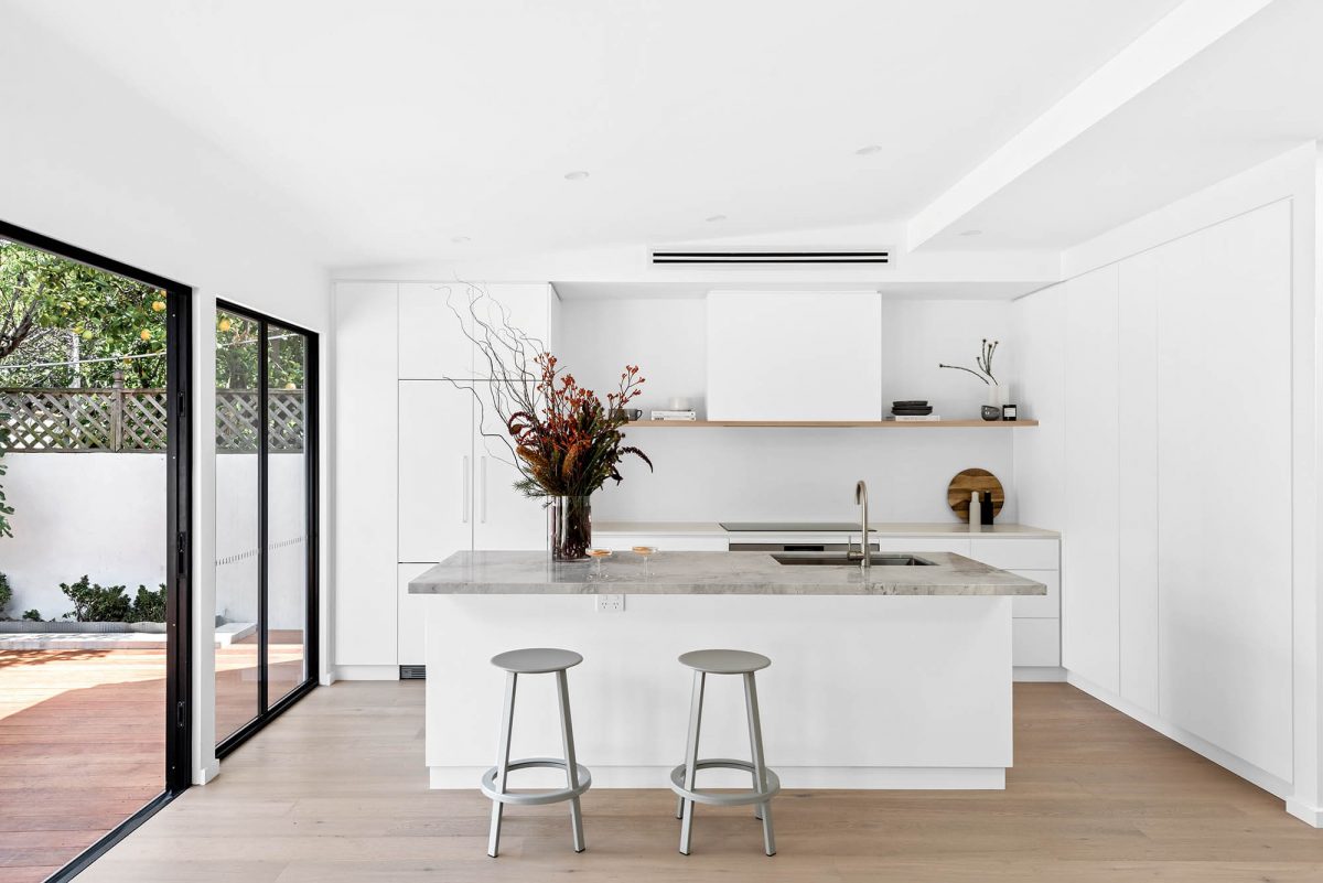 A custom designed kitchen featuring a stone benchtop and white custom joinery. Designed and built by MJ Harris Group.