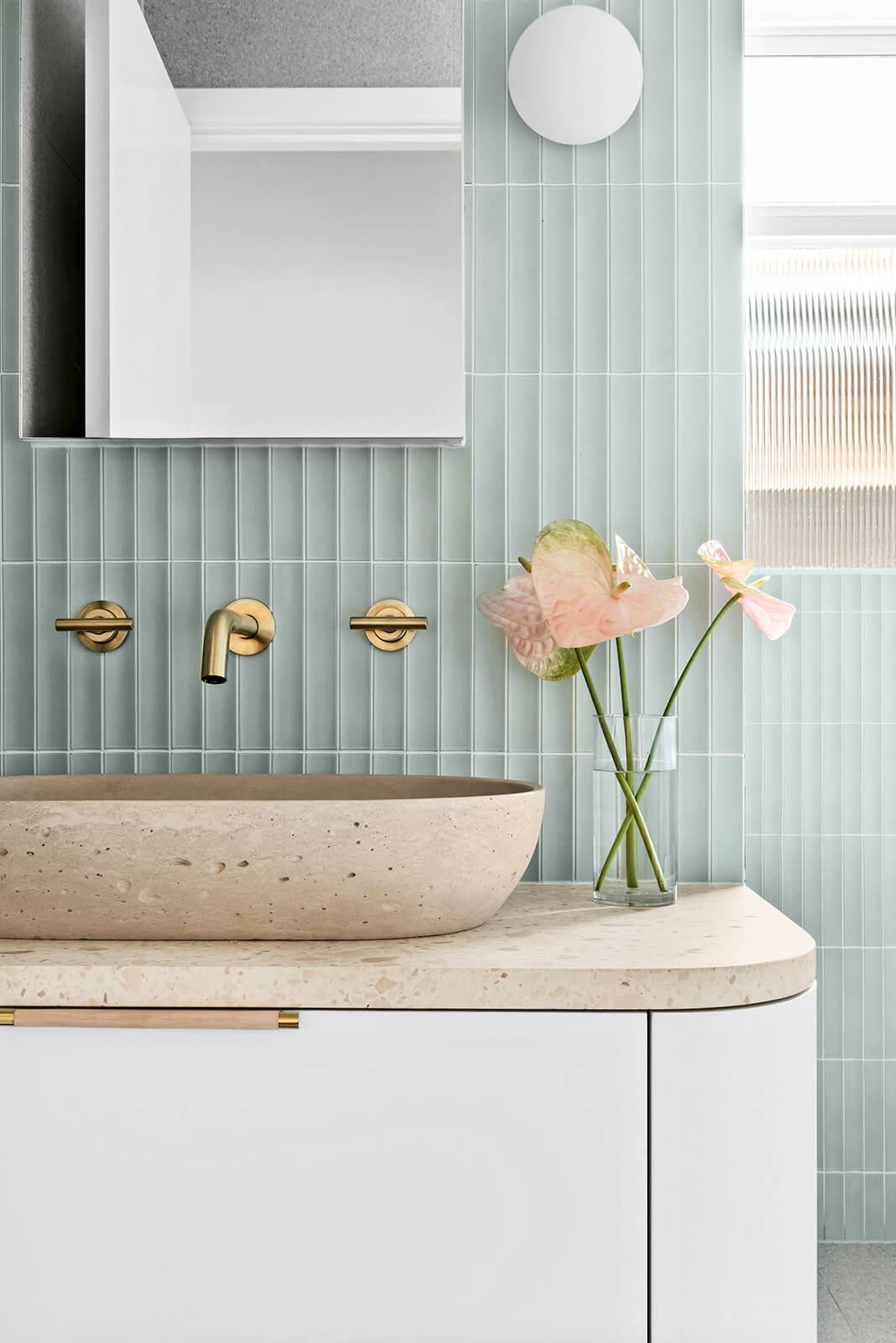 A custom designed bathroom featuring green concave kit kat tile feature wall and pink concrete basin. Designed and built by MJ Harris Group.