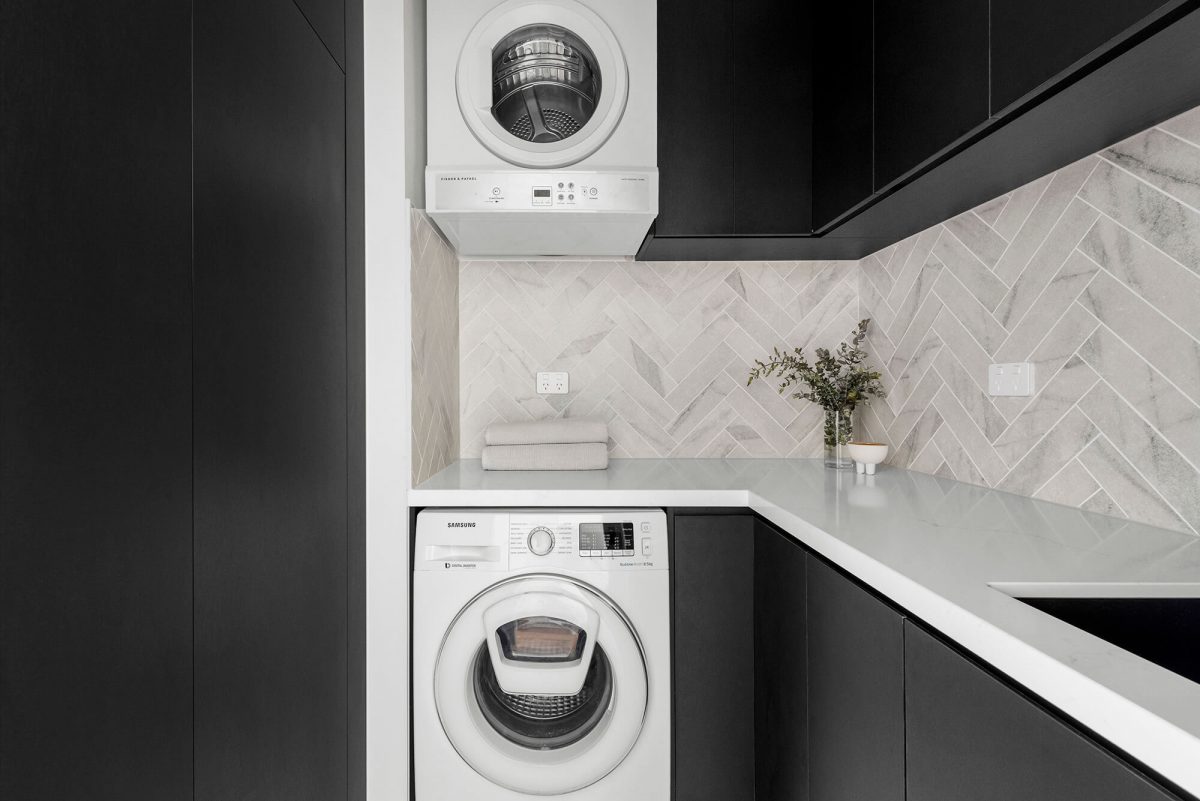 A custom designed laundry featuring a tiled herringbone splashback and custom joinery. Designed and built by MJ Harris Group. #MJHxBaySt