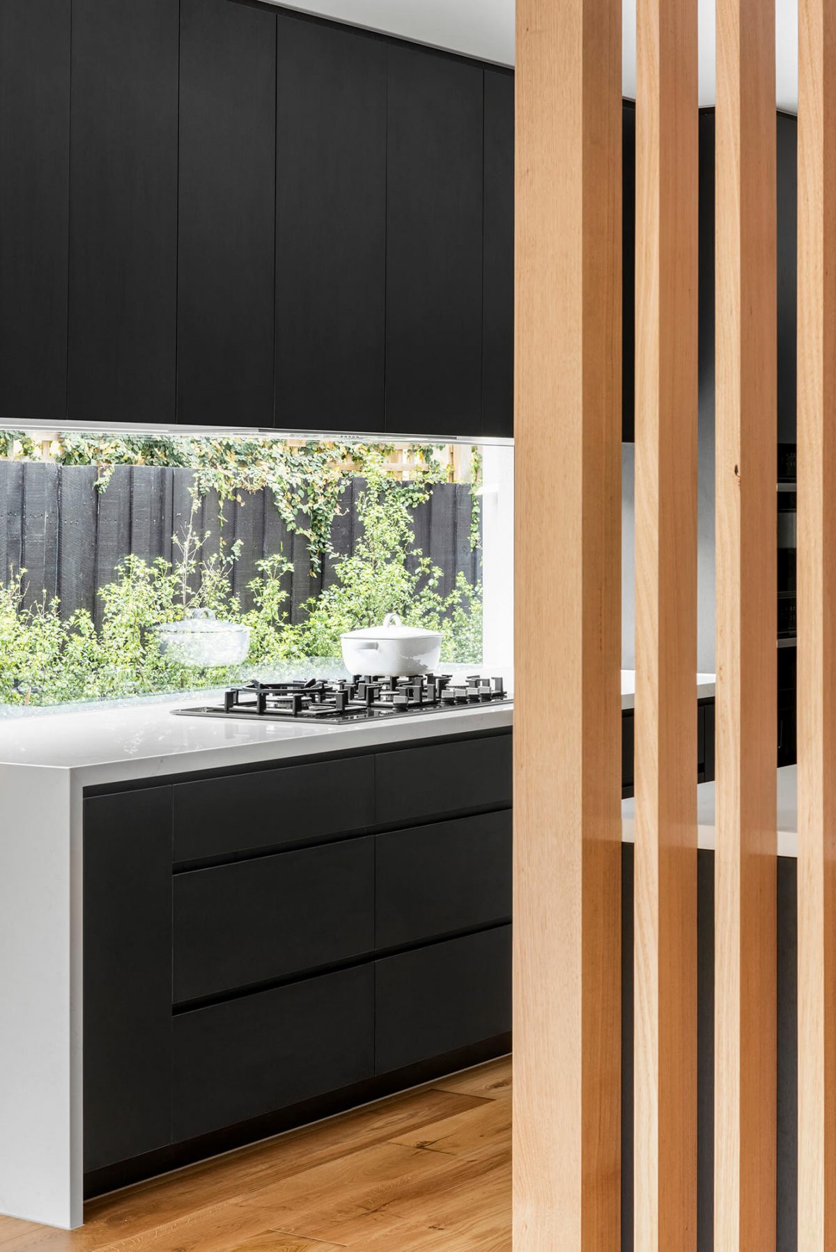 A custom designed kitchen featuring a monochrome style and timber batten. Designed and built by MJ Harris Group. #MJHxBaySt