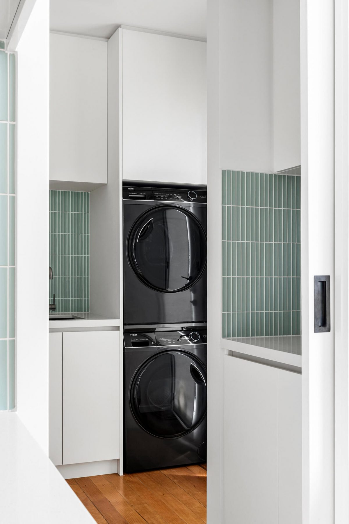 Melbourne combined space kitchen renovation butlers pantry and laundry room green concave tiles, white custom joinery, brushed gunmetal tapware, black washing machine, black dryer