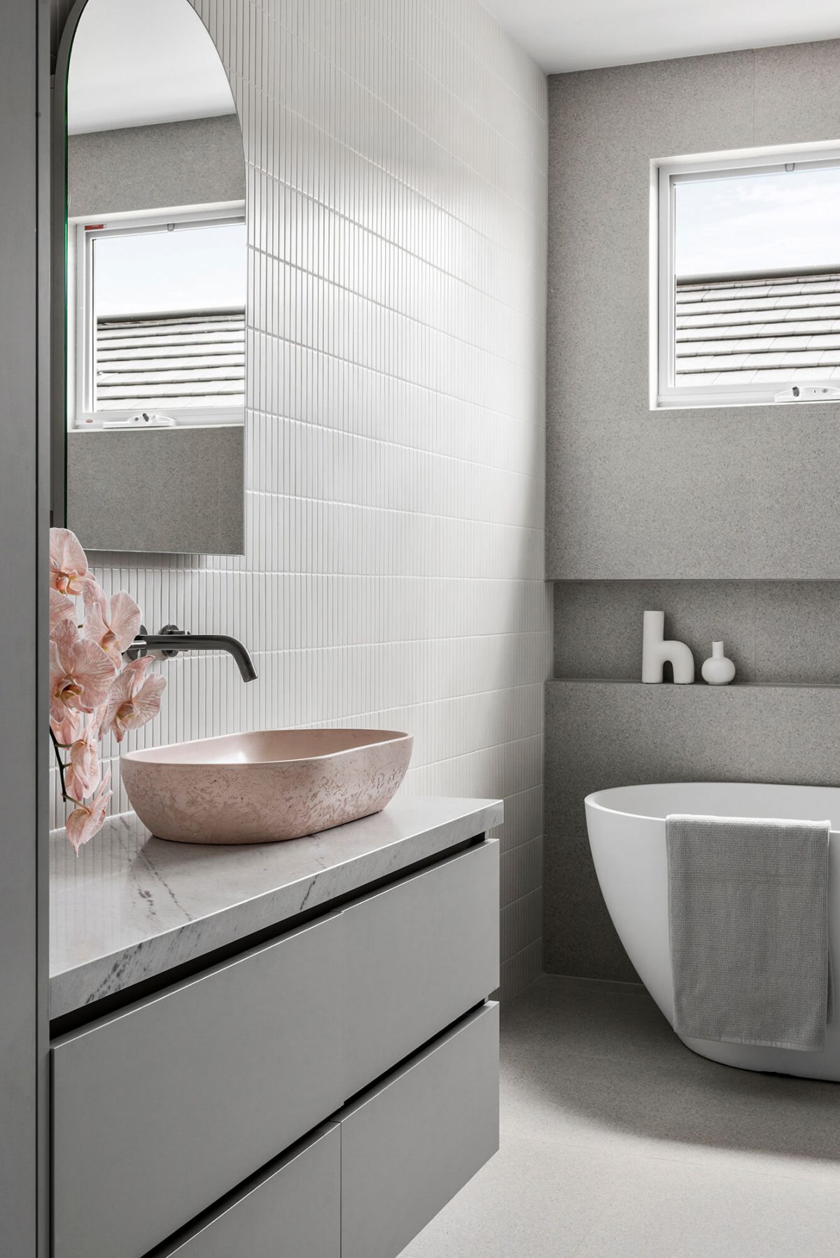 Bathroom renovation Brighton, Melbourne - free-standing bath, walk-in shower, in wall niche, kitkat feature wall, custom joinery, pink concrete basin, arch mirror, wall sconces, linen cabinet, terrazzo tile