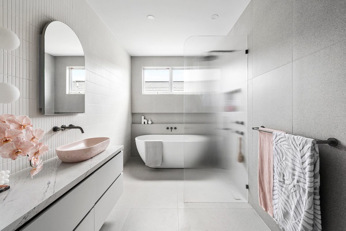 large bathroom, free-standing bath, walk-in shower, in wall niche, kitkat feature wall, custom joinery, pink concrete basin, arch mirror, wall sconces, linen cabinet, terrazzo tile