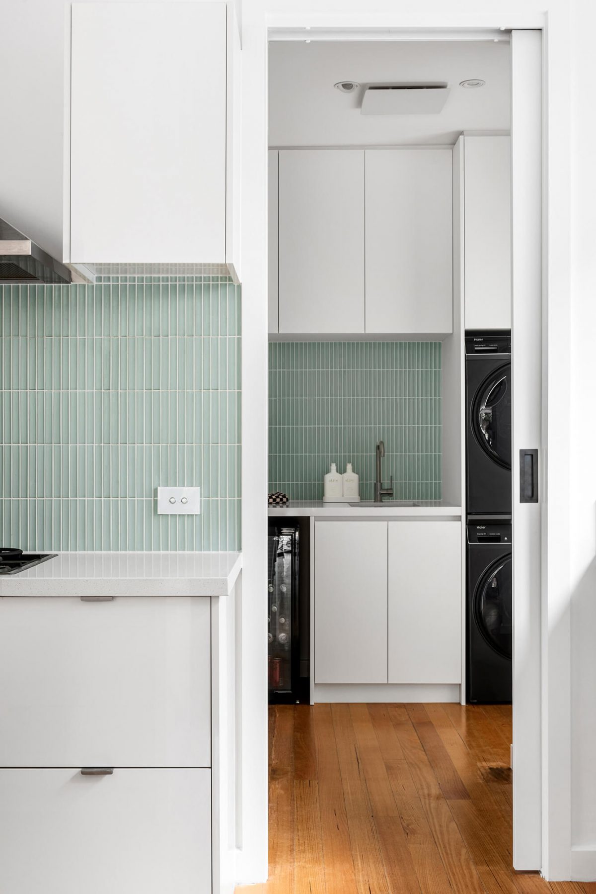 Brighton combined space kitchen renovation butlers pantry and laundry room green concave tiles, white custom joinery, brushed gunmetal tapware, black washing machine, black dryer