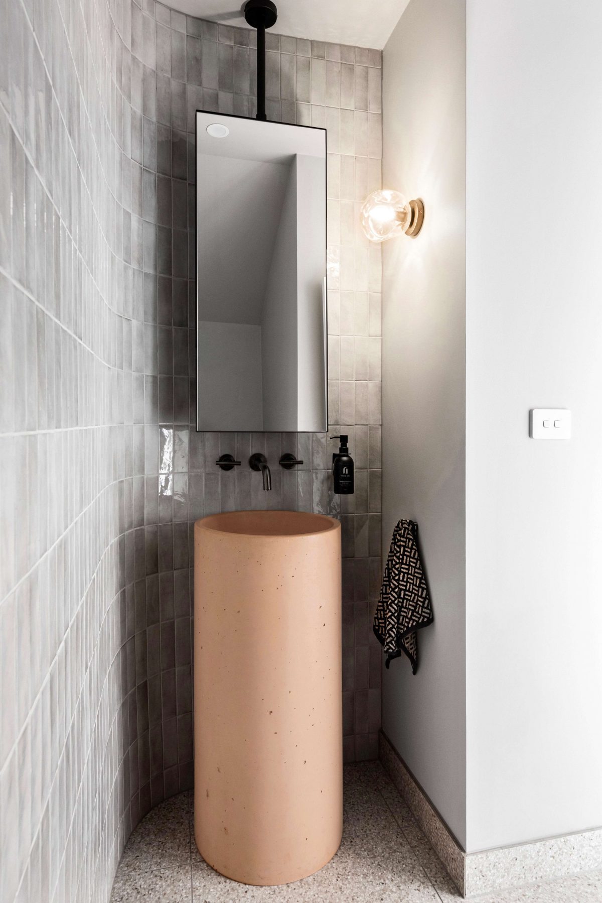 A custom designed bathroom featuring a curved tiled feature wall and pink concrete pillar basin. Designed and built by MJ Harris Group. #MJHxPeppinSt