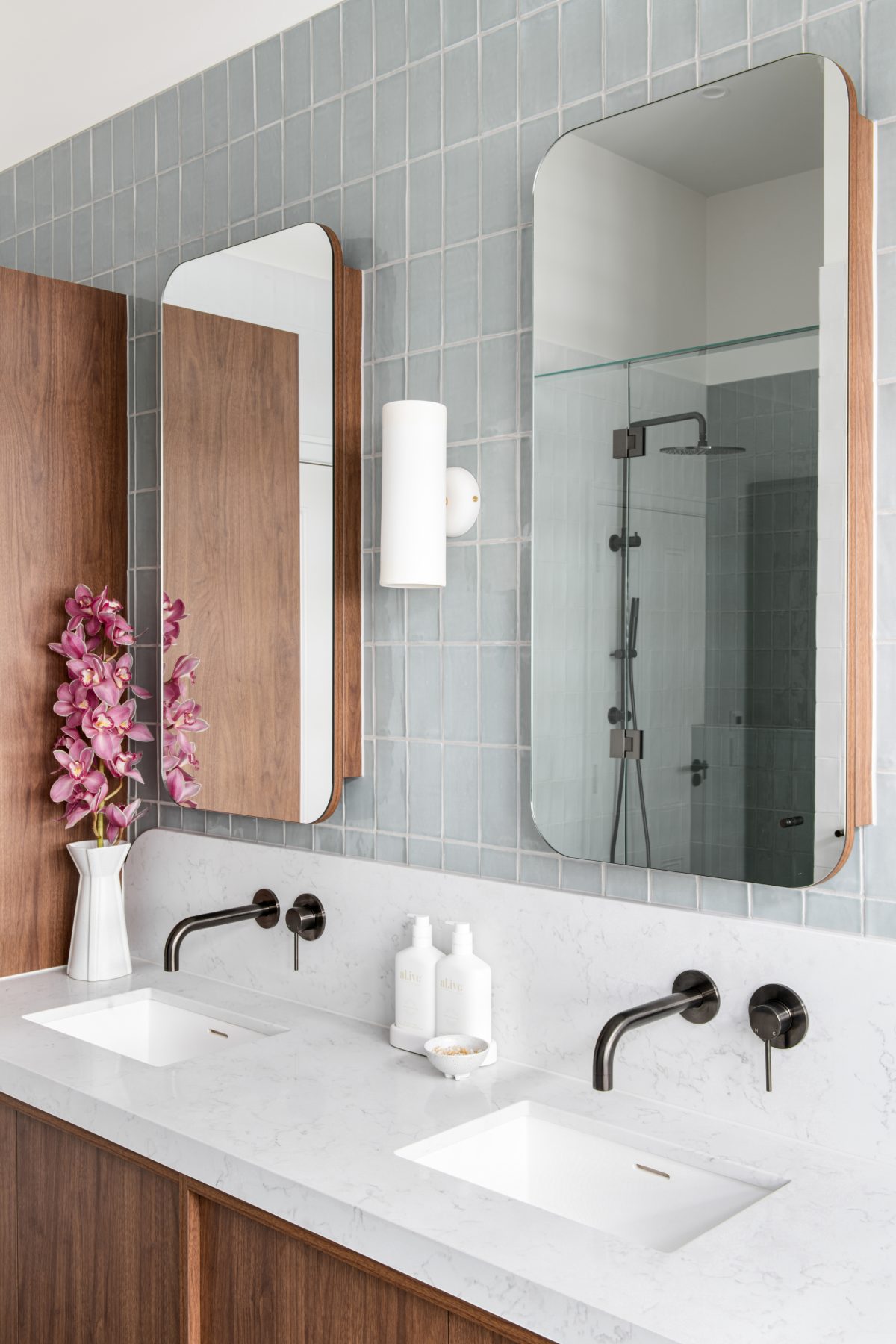 A custom designed bathroom featuring walnut joinery and Spanish handmade look tiles. Designed and built by MJ Harris Group.