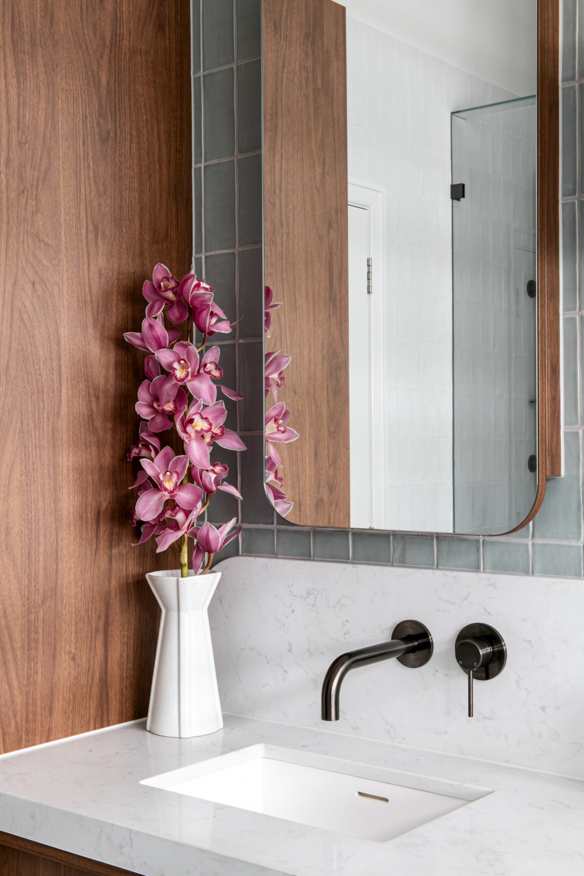 A custom designed bathroom featuring walnut joinery and Spanish handmade look tiles. Designed and built by MJ Harris Group.