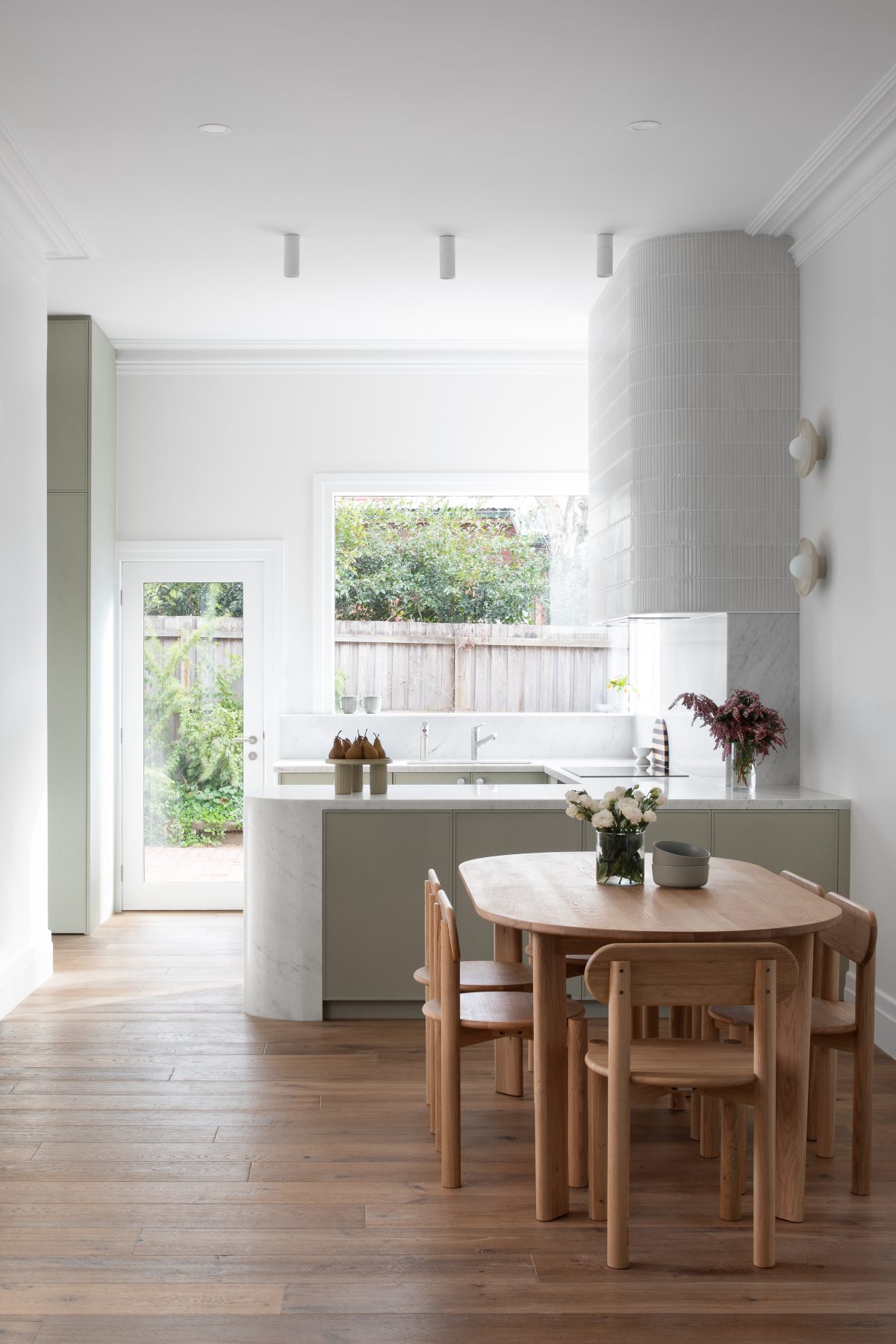 A custom designed kitchen featuring custom joinery in green and a Carrara Marble bench top. Designed and built by MJ Harris Group.