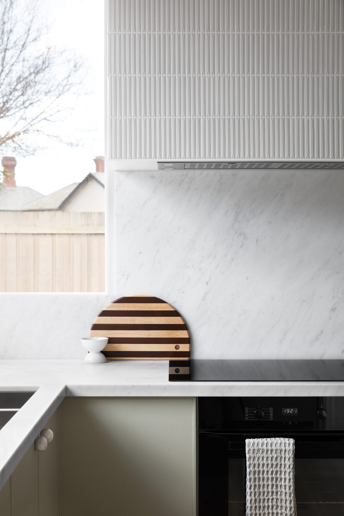 A custom designed kitchen featuring custom joinery in green and a Carrara Marble bench top and splashback. Designed and built by MJ Harris Group.