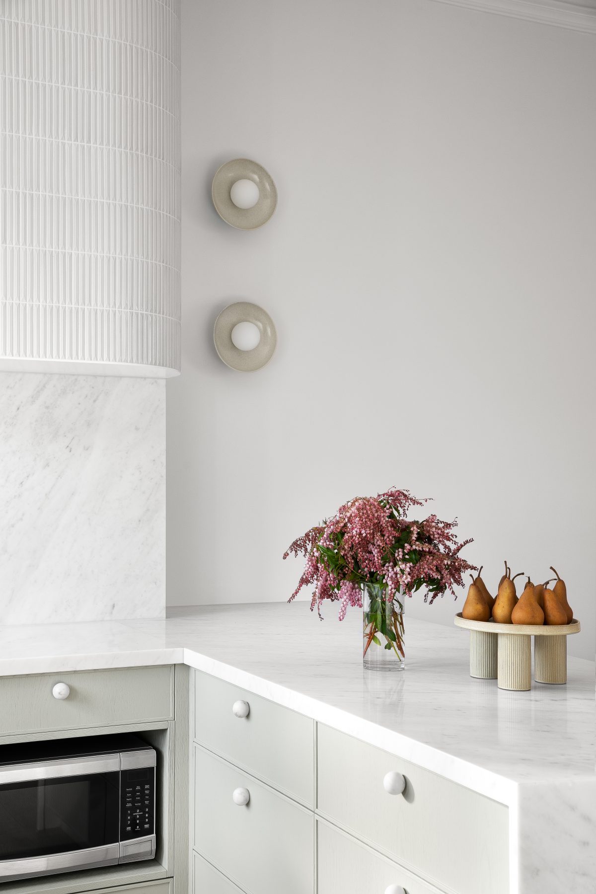 A custom designed kitchen featuring custom joinery in green and a Carrara Marble bench top. Designed and built by MJ Harris Group.