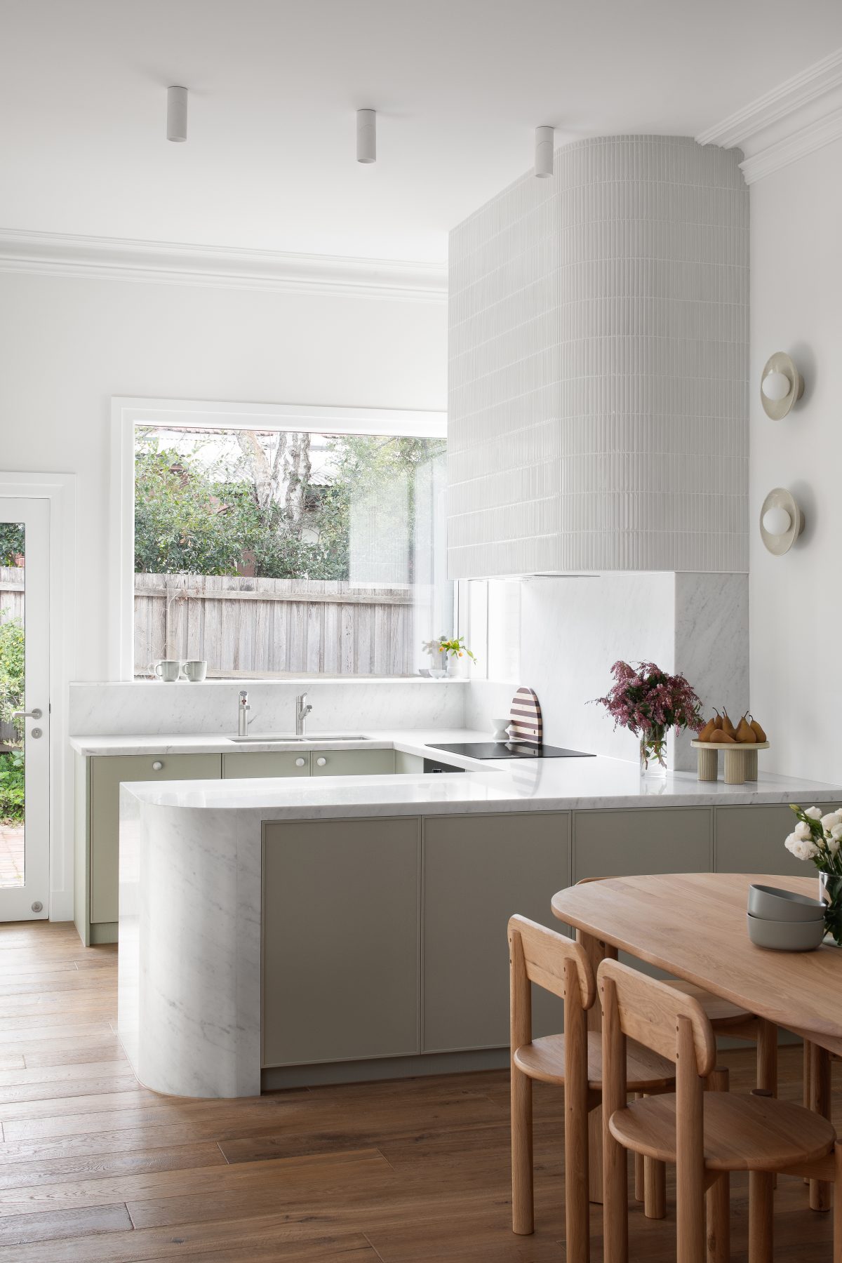 A custom designed kitchen featuring custom joinery in green and a Carrara Marble bench top. Designed and built by MJ Harris Group.