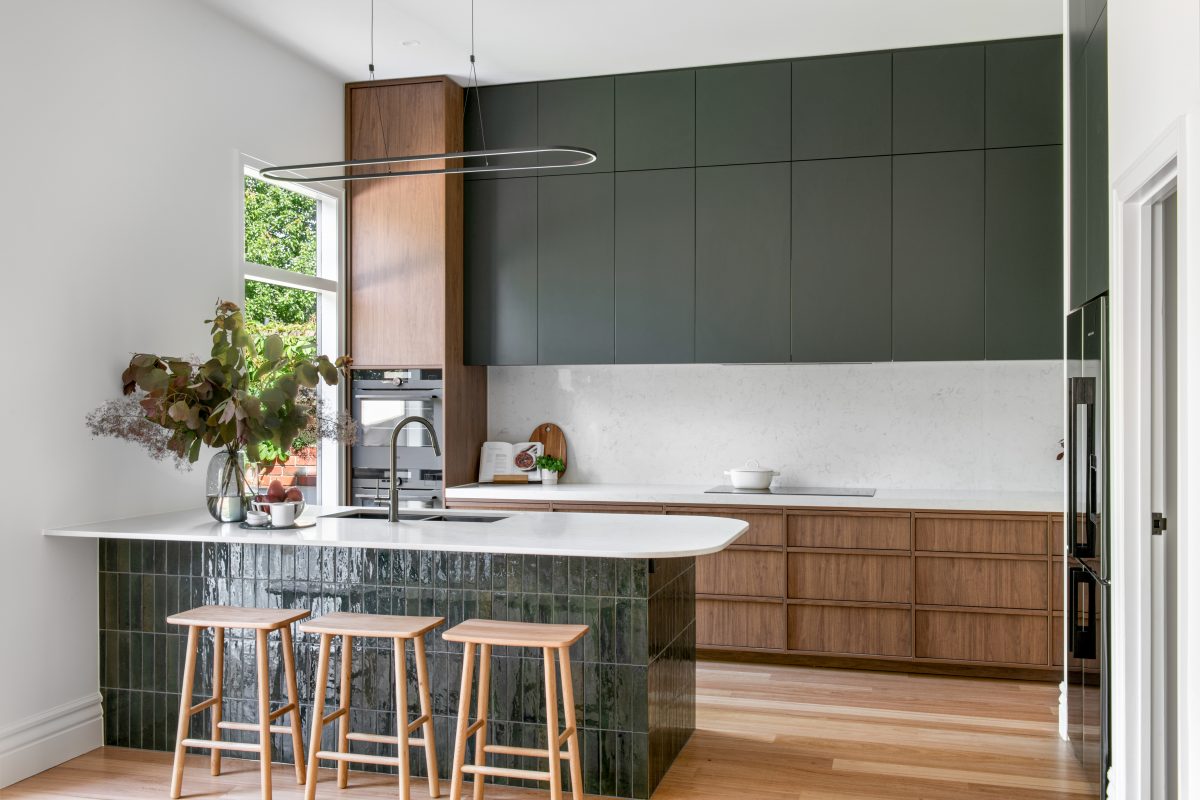 A custom designed kitchen featuring walnut joinery and handmade gloss green tiles. Designed and built by MJ Harris Group.