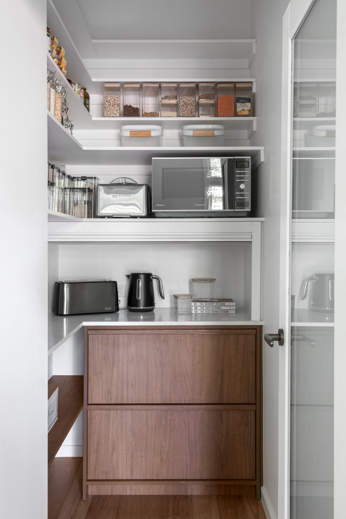 A custom designed pantry featuring walnut joinery. Designed and built by MJ Harris Group.