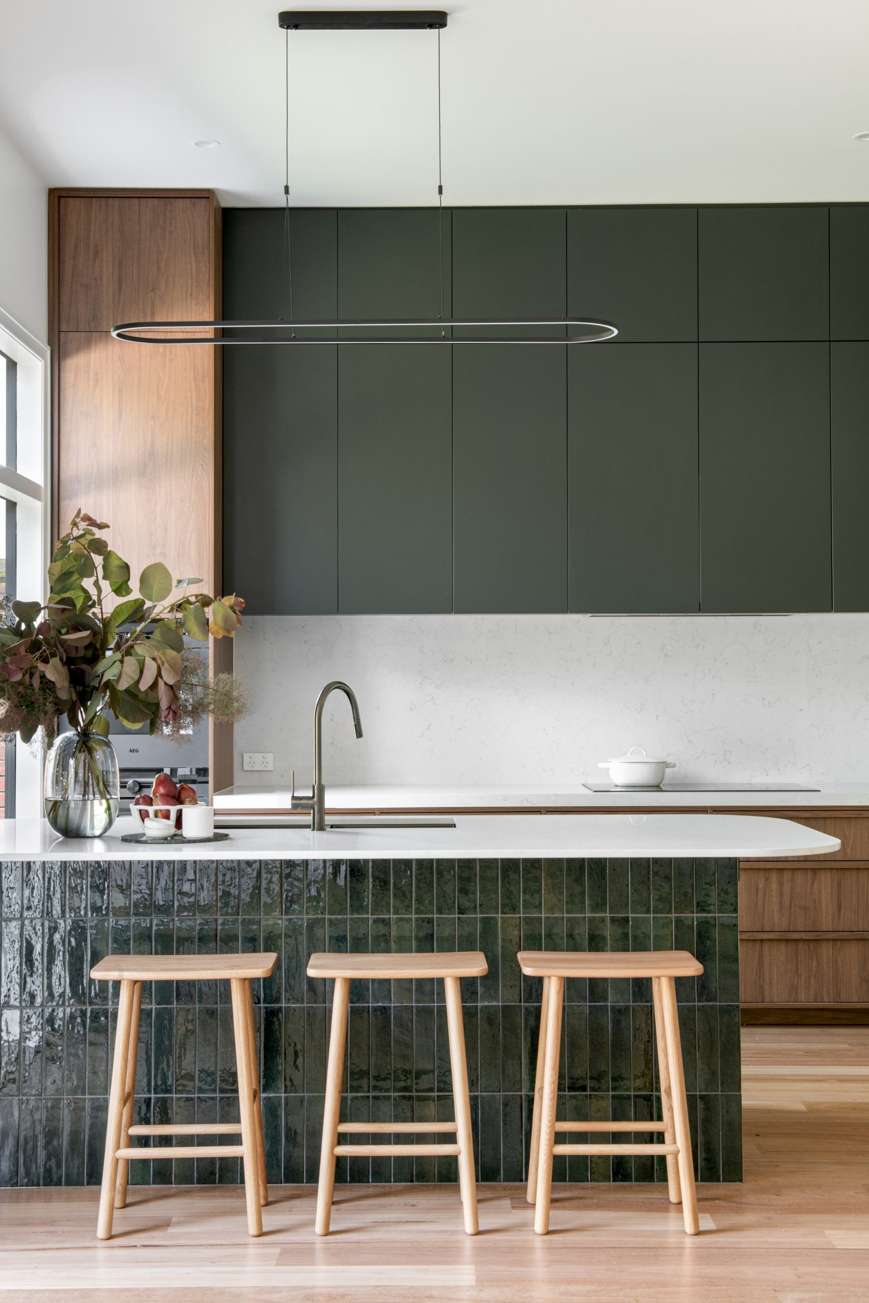 A custom designed kitchen featuring walnut joinery and handmade gloss green tiles. Built by M.J. Harris Group